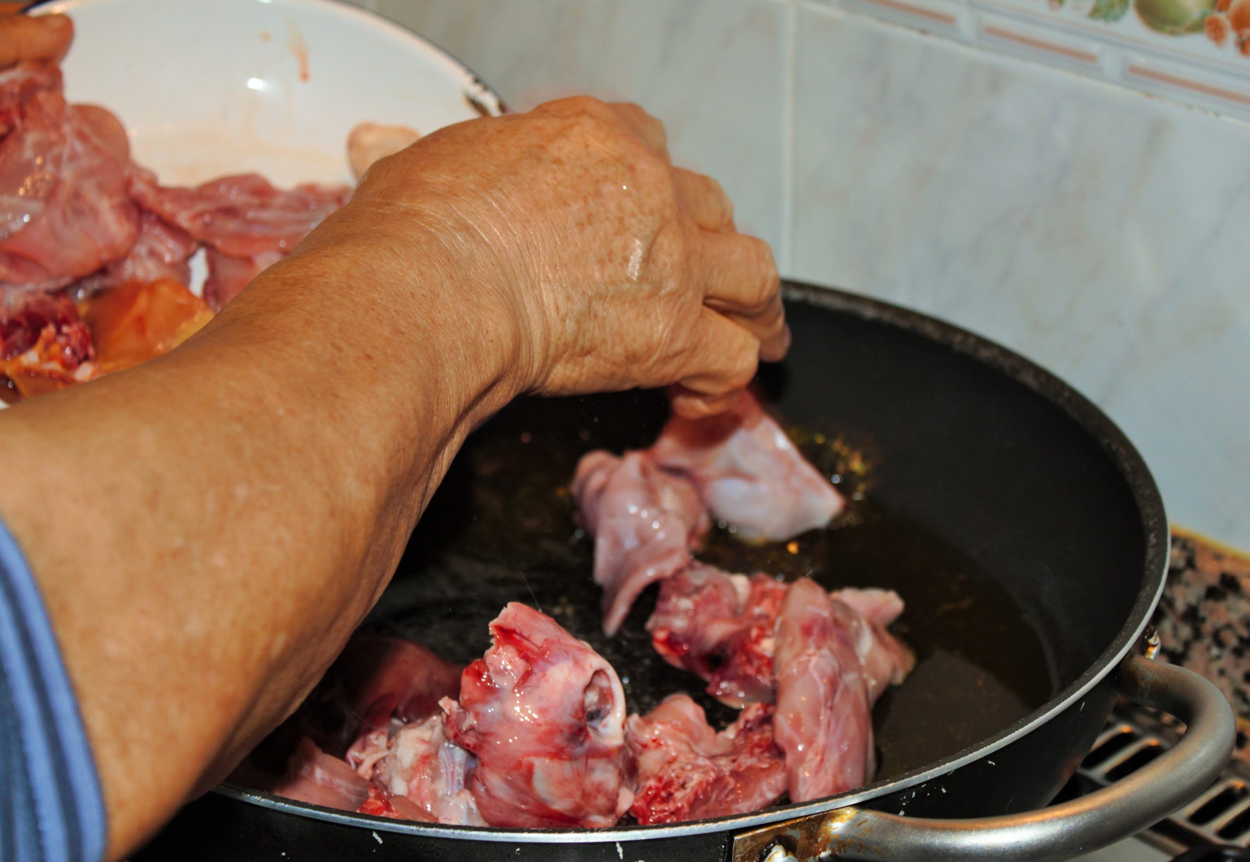 Dorado del conejo troceado en la paella para el arroz con alcachofas