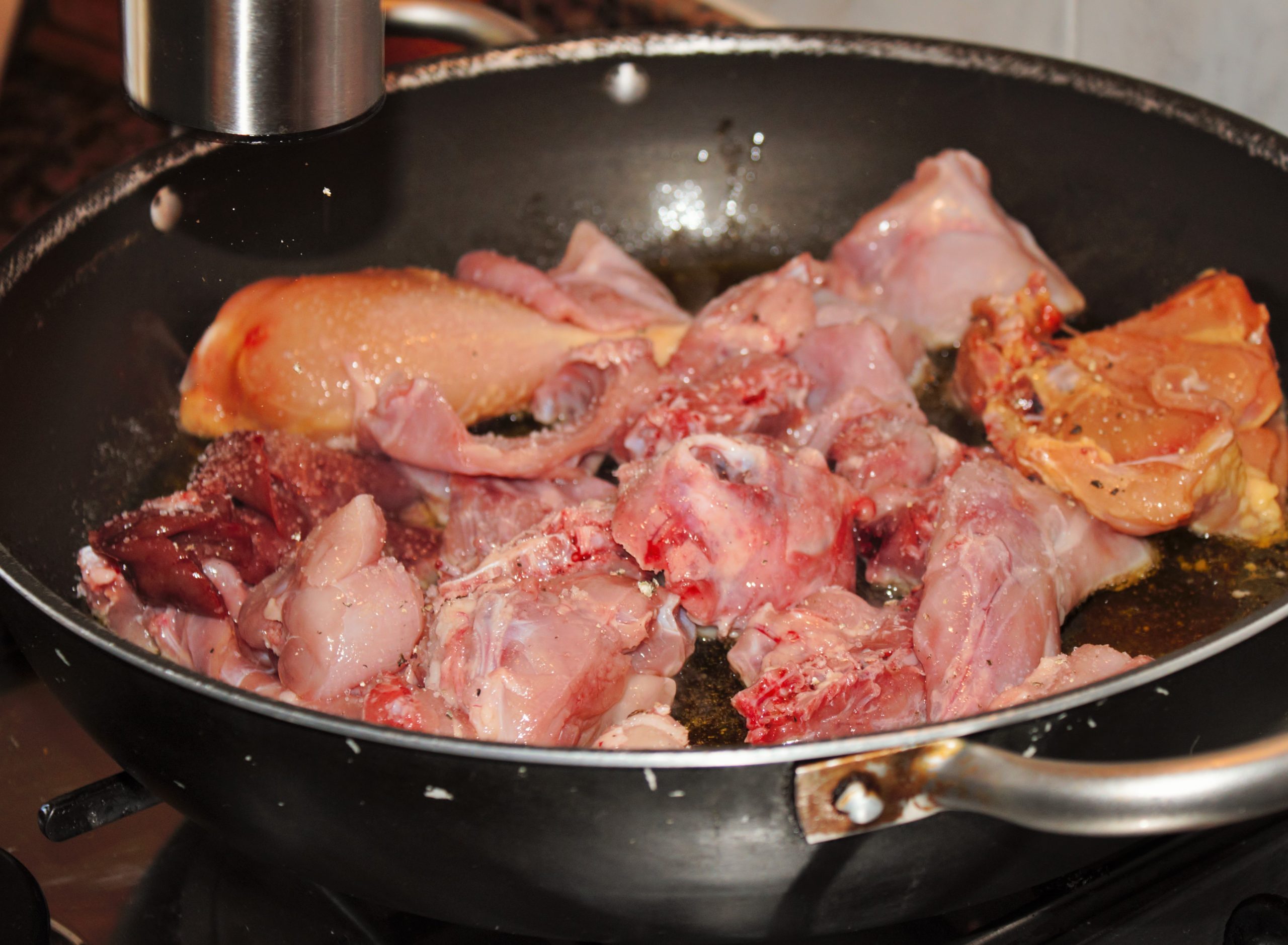 salpimentando la carne en la paella para el arroz