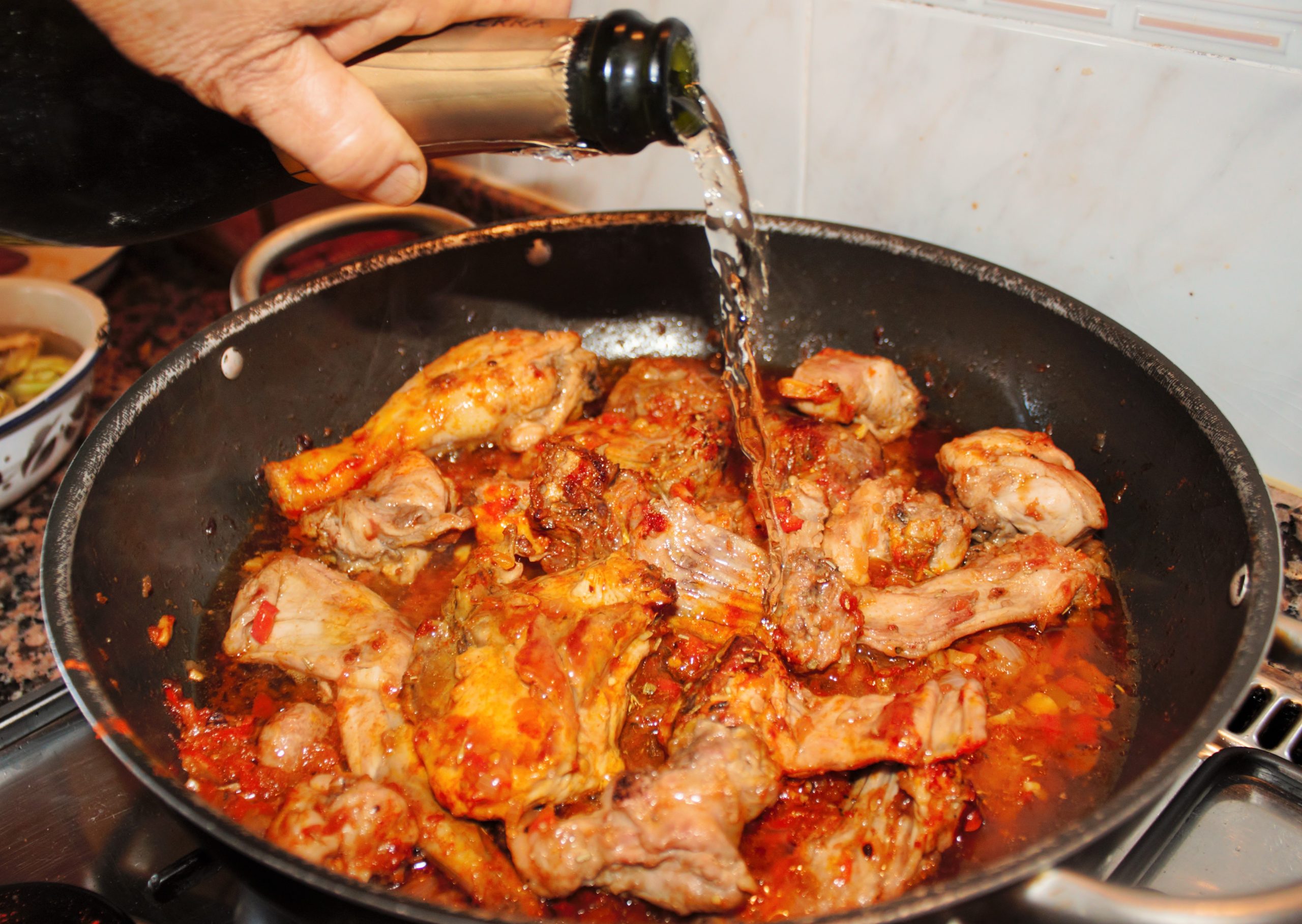 Vertiendo una copa de cava para desglasar el sofrito de conejo