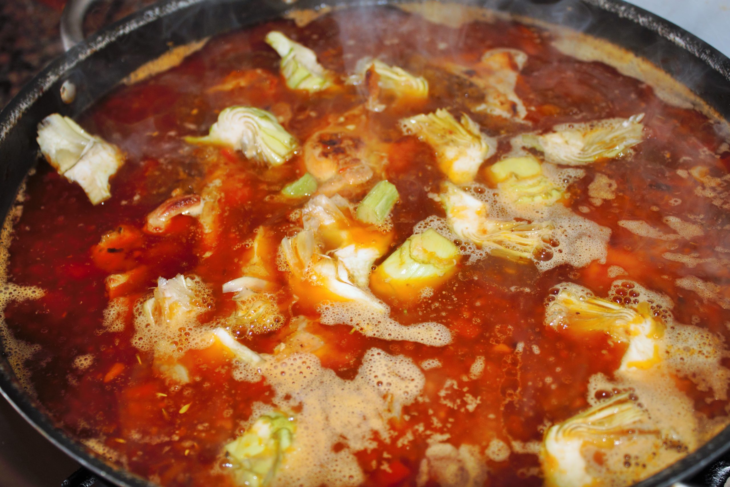 Añadiendo las alcachofas al agua del sofrito de conejo