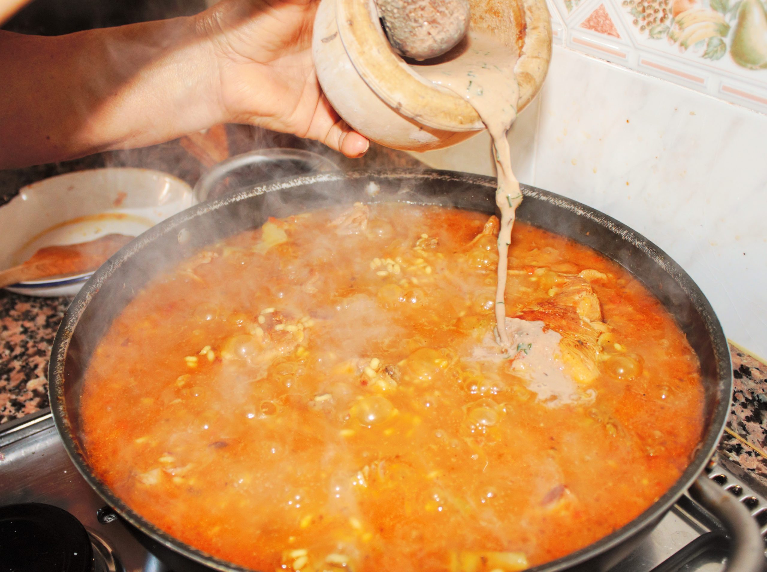 Añadiendo la picada tradicional de hígado de conejo para espesar y dar sabor al arroz