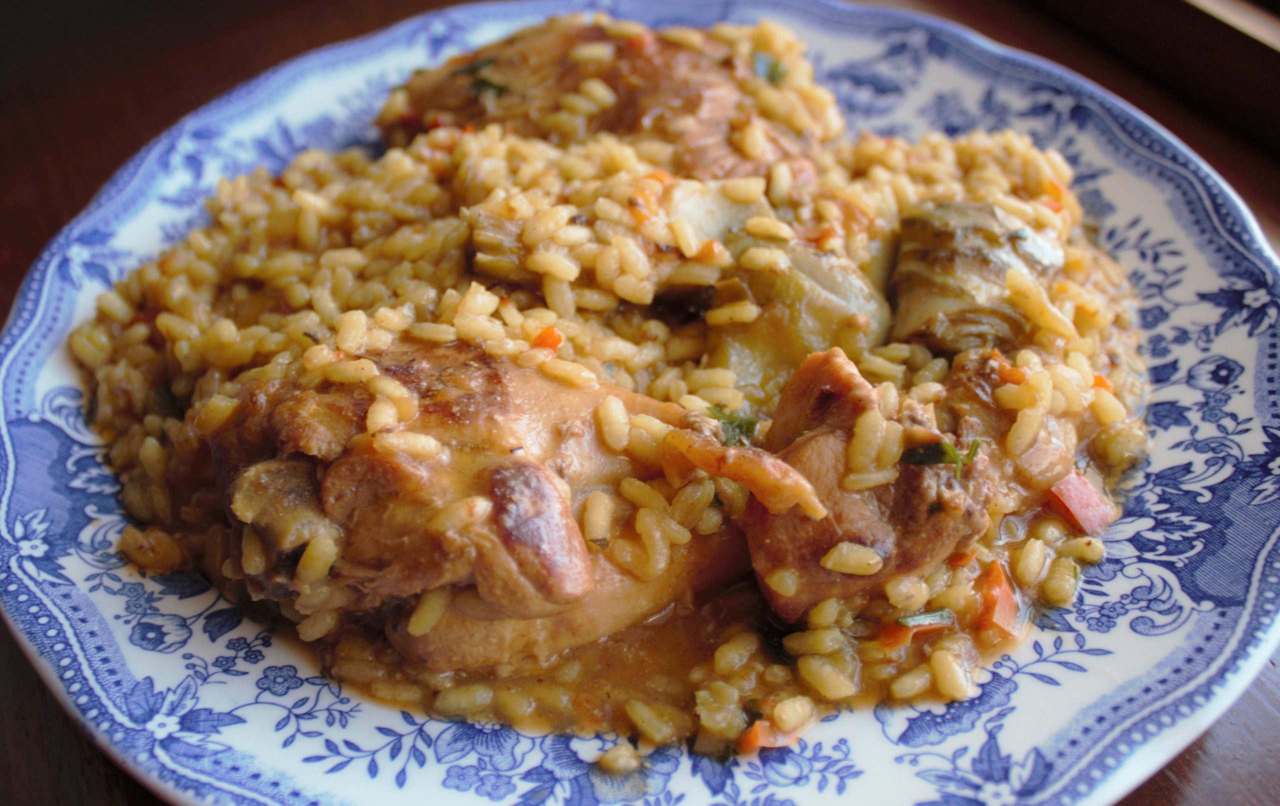 Arroz de conejo y alcachofas tradicional servido en plato azul y blanco