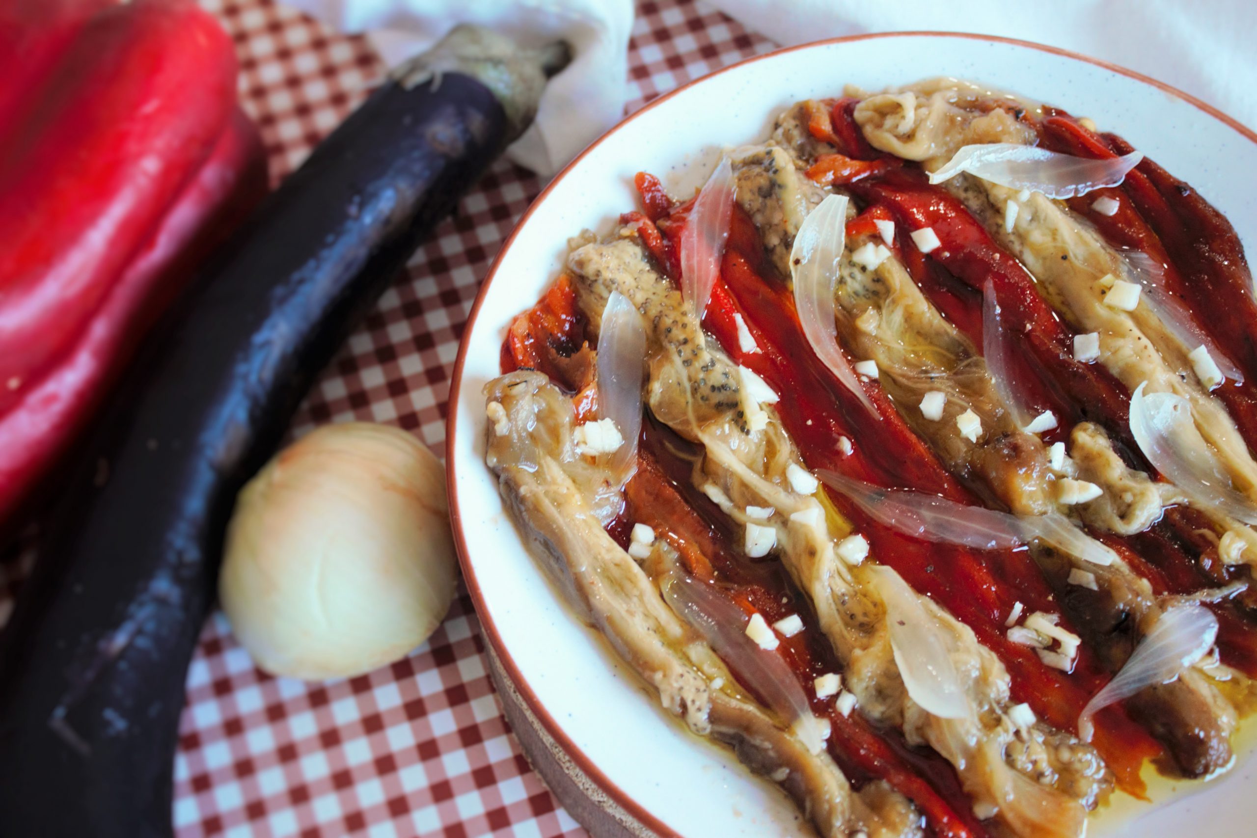 Escalivada catalana tradicional con pimientos rojos, berenjenas y cebolla asada presentada en un plato rústico con aceite de oliva.