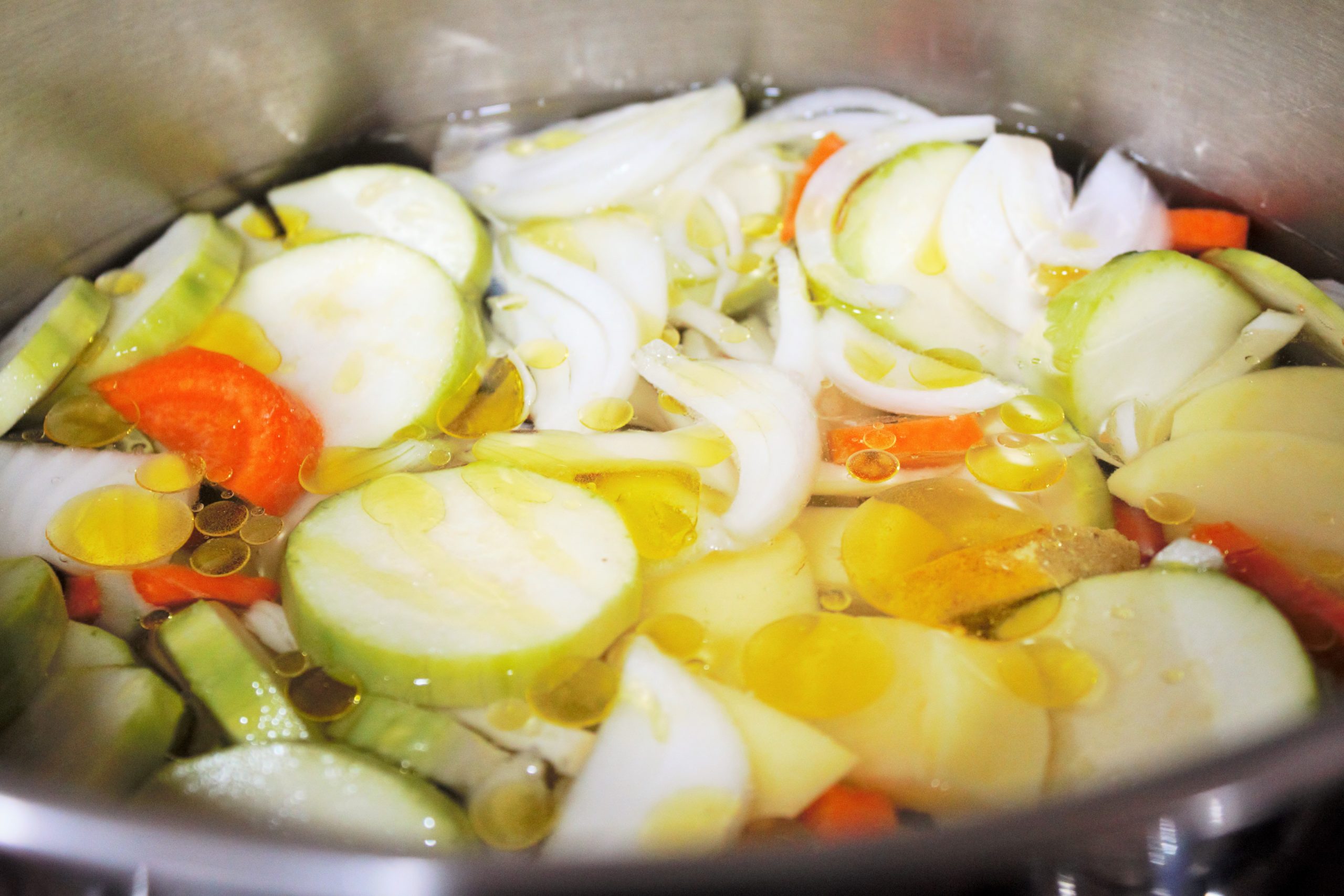 Verduras cociendo suavemente en caldo natural, capturando el vapor y la esencia de la cocina tradicional.