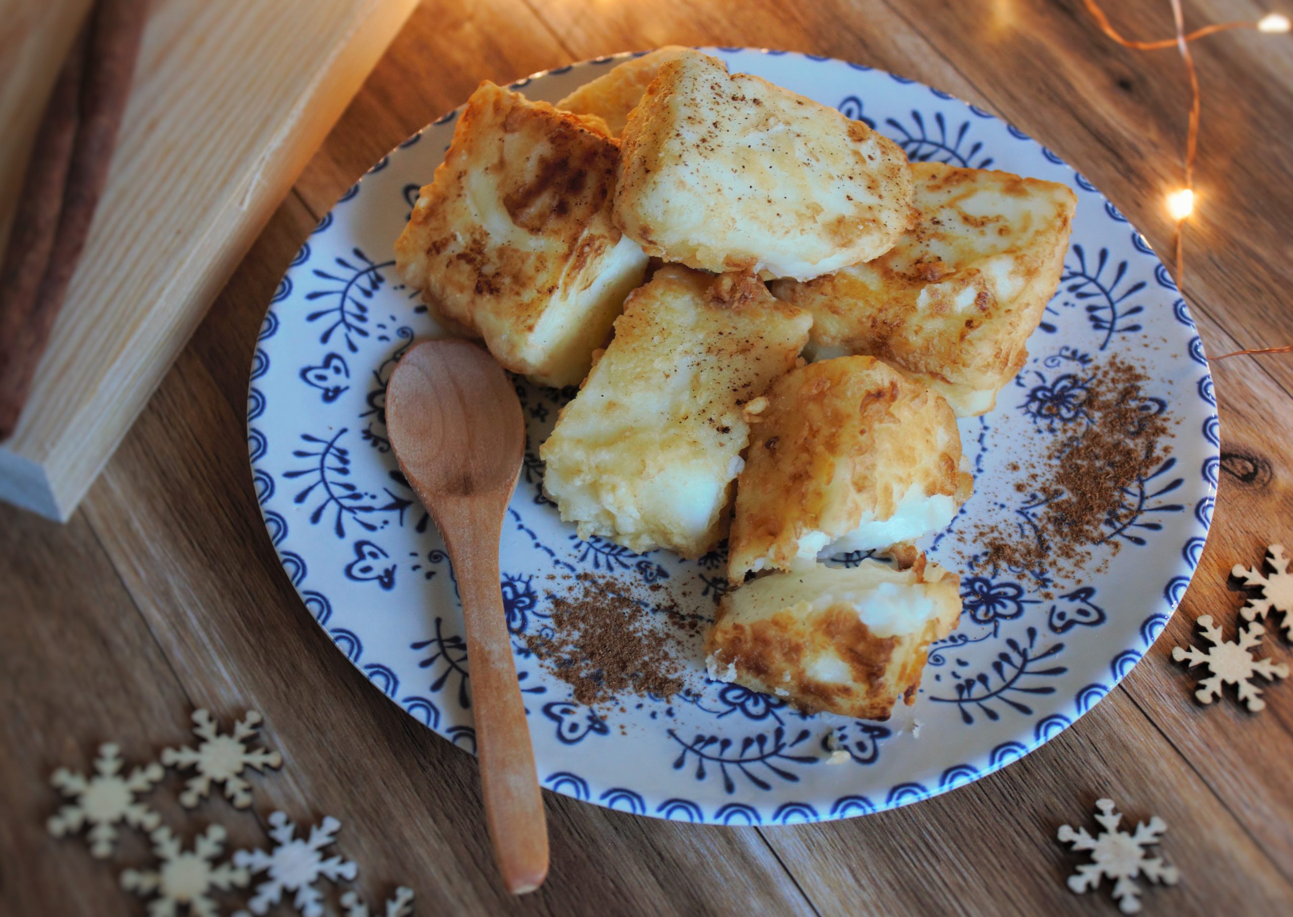 Plato de leche frita casera rebozada en az&uacute;car y canela con corteza de lim&oacute;n.