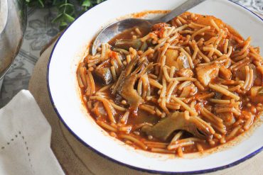 Plato de fideos a la cazuela tradicionales con costilla de cerdo y alcachofas.