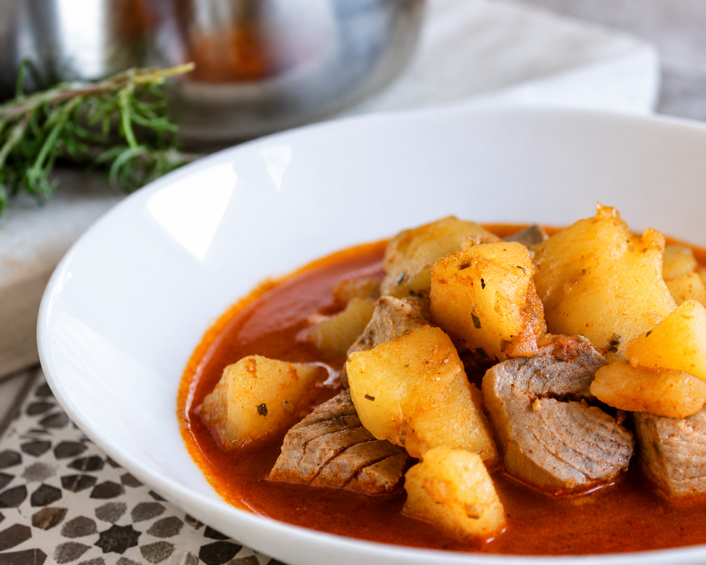 Cazuela de Marmitako de atún con patatas chascadas, pimientos y un caldo espeso de color rojizo.