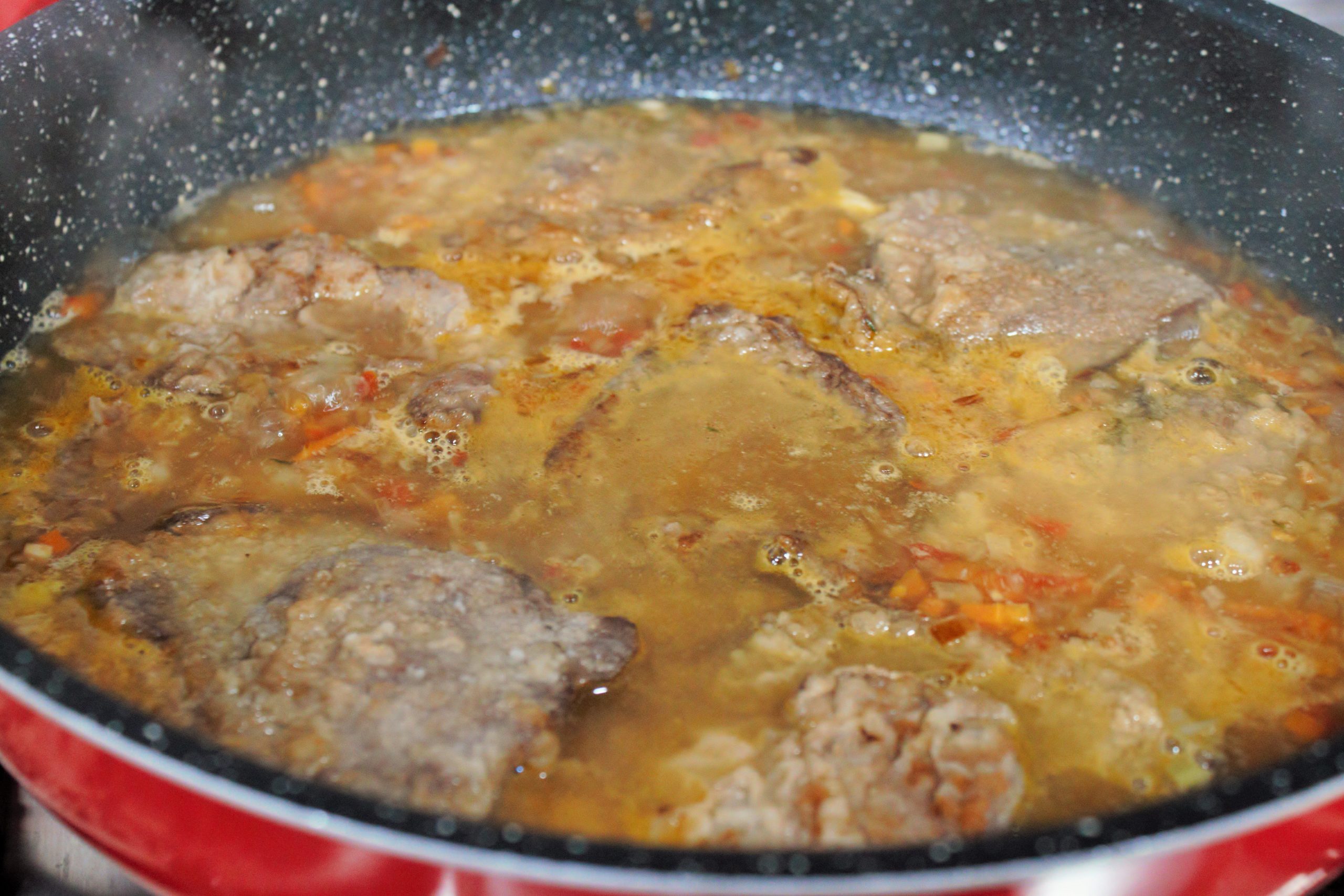 Cubriendo la carne sellada con caldo de carne en la cazuela para empezar la cocción lenta.