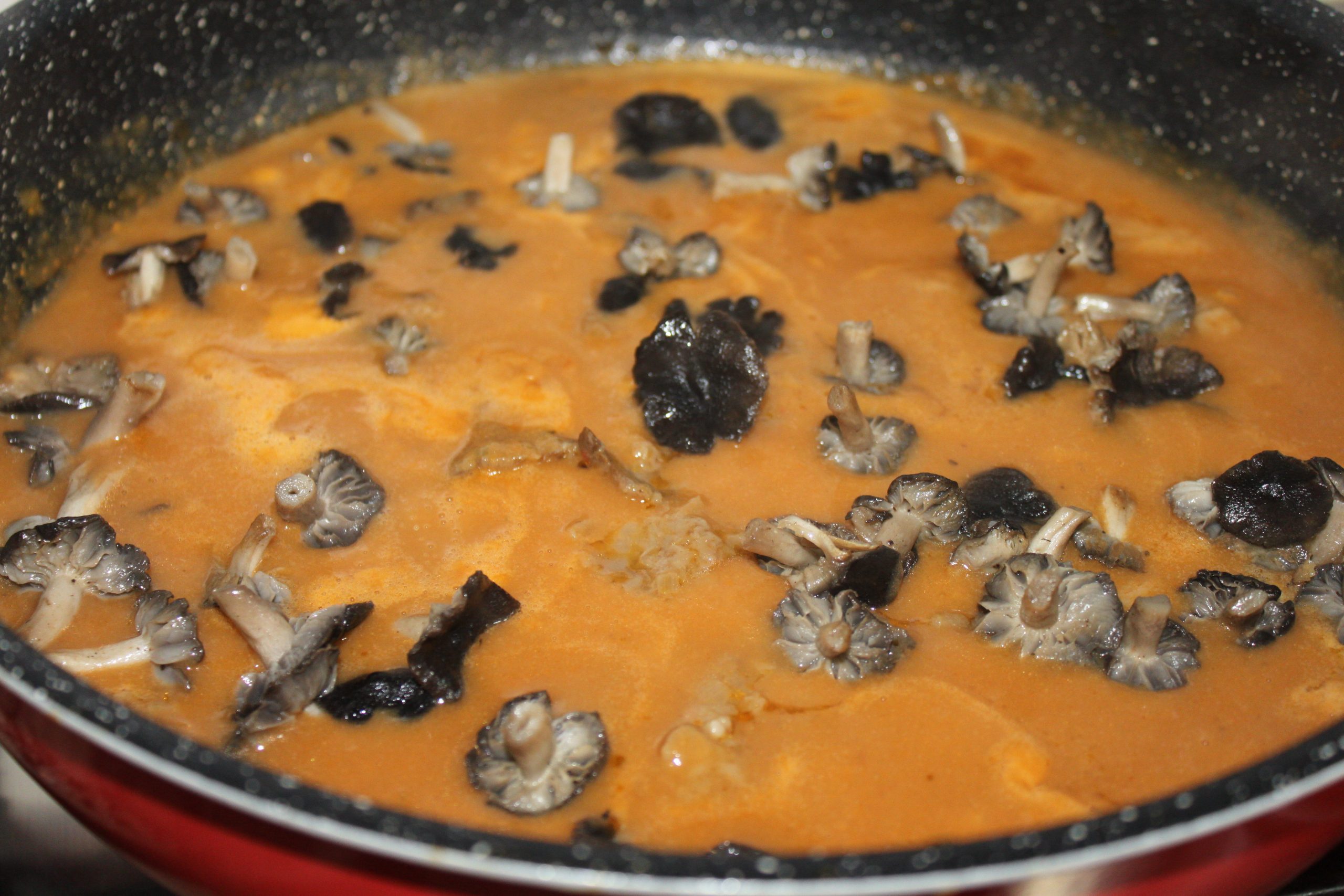 Añadiendo los fredolics salteados y la carne a la salsa triturada en la cazuela.
