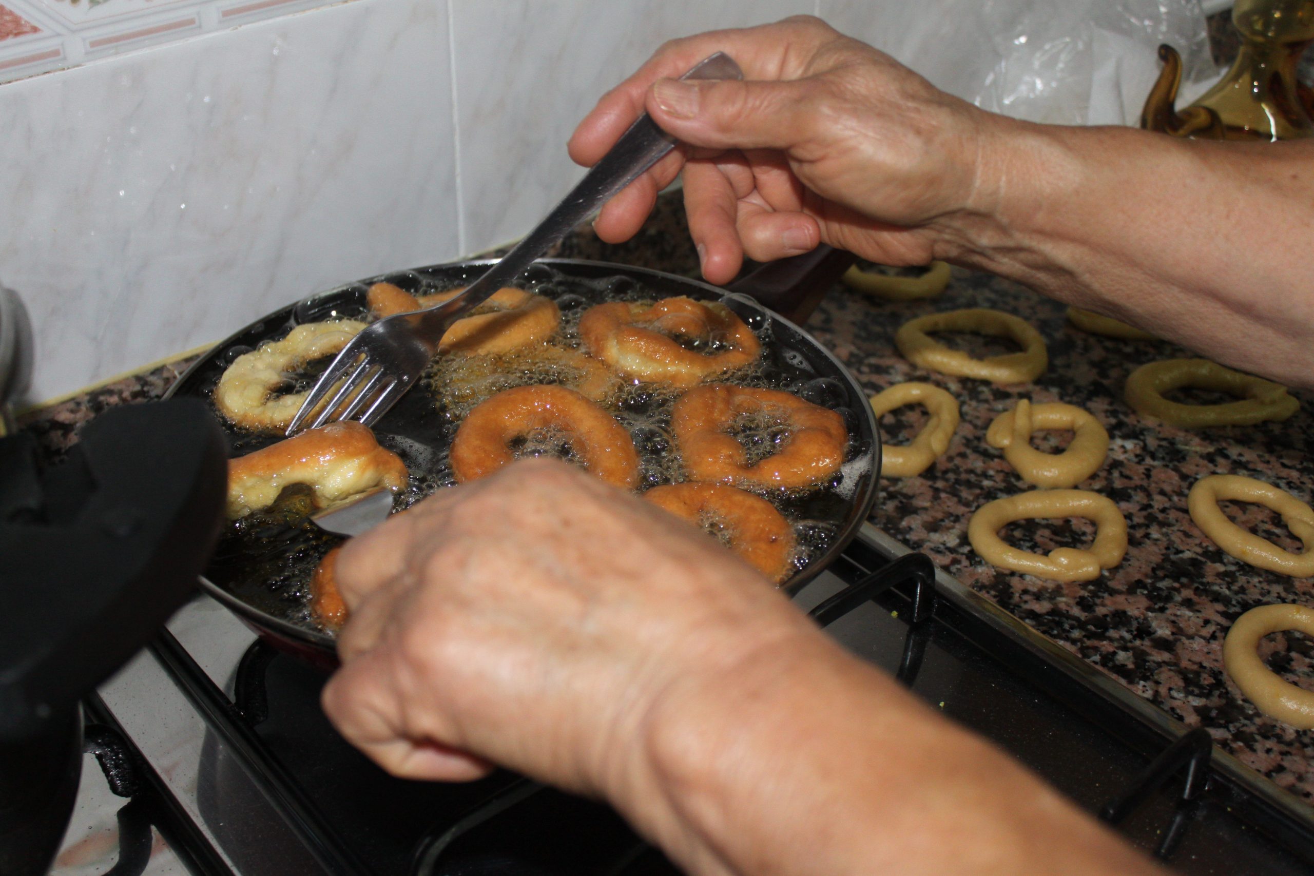 Roscos de anís friéndose en aceite caliente hasta quedar dorados y crujientes.