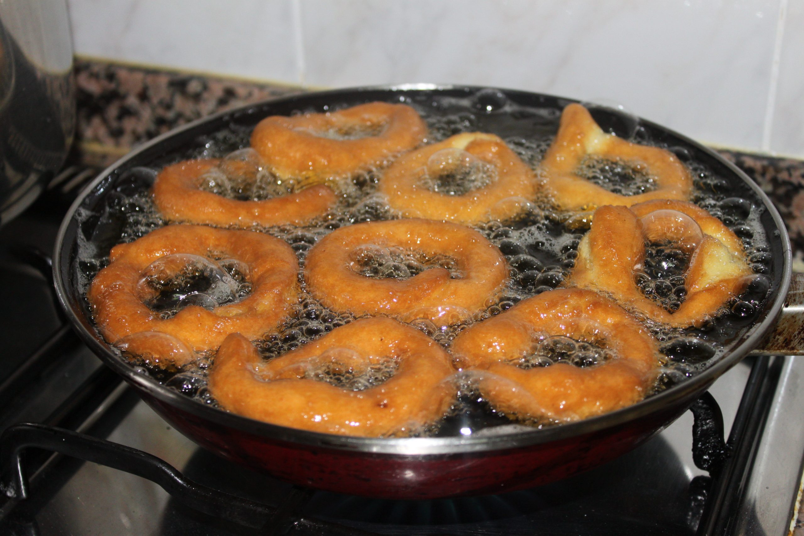 Roscos de anís tradicionales cocinándose en una sartén con abundante aceite.