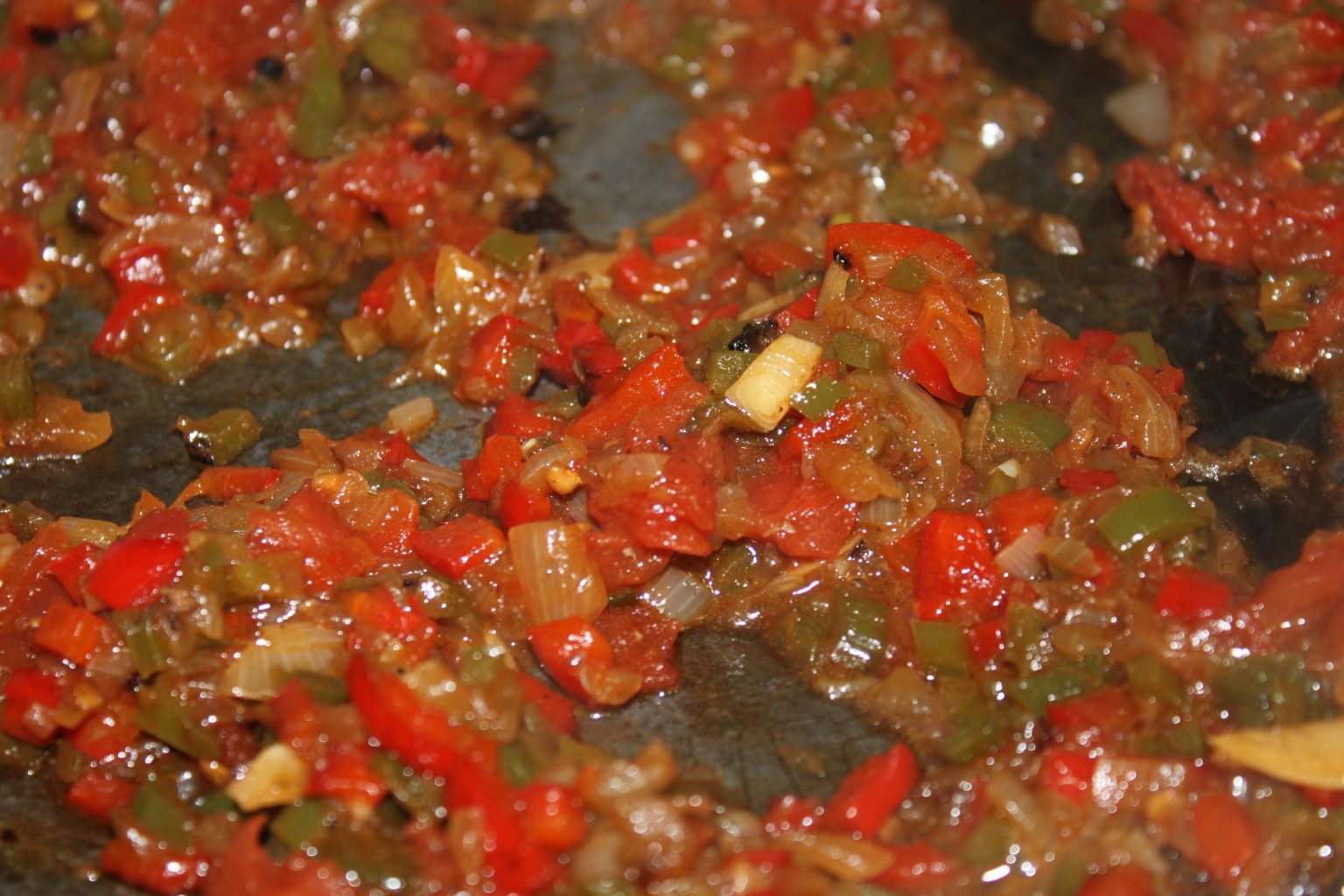 Añadiendo el tomate al sofrito de verduras reducido de nuestra paella de marisco