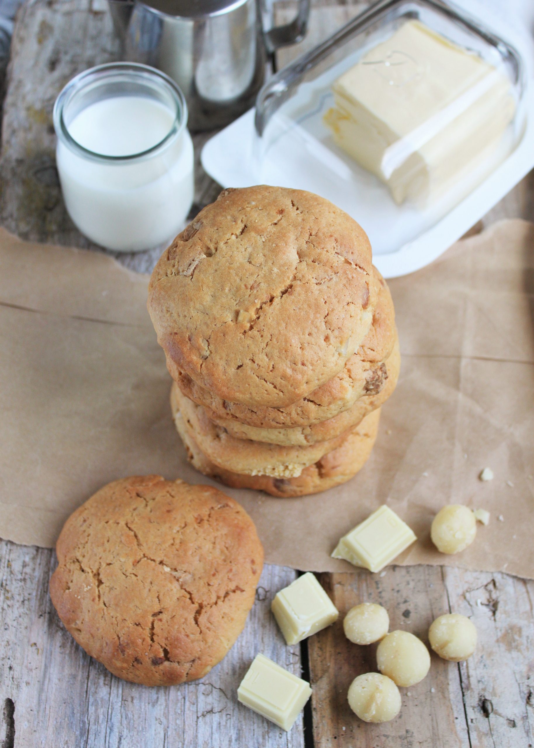 Galletas caseras de chocolate blanco y nueces de macadamia con bordes dorados, sobre una rejilla de enfriar en una cocina con luz natural cálida