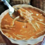 Sopa de pescado tradicional con fideos y base de pan duro triturado, servida en plato hondo con trozos de pescado blanco.