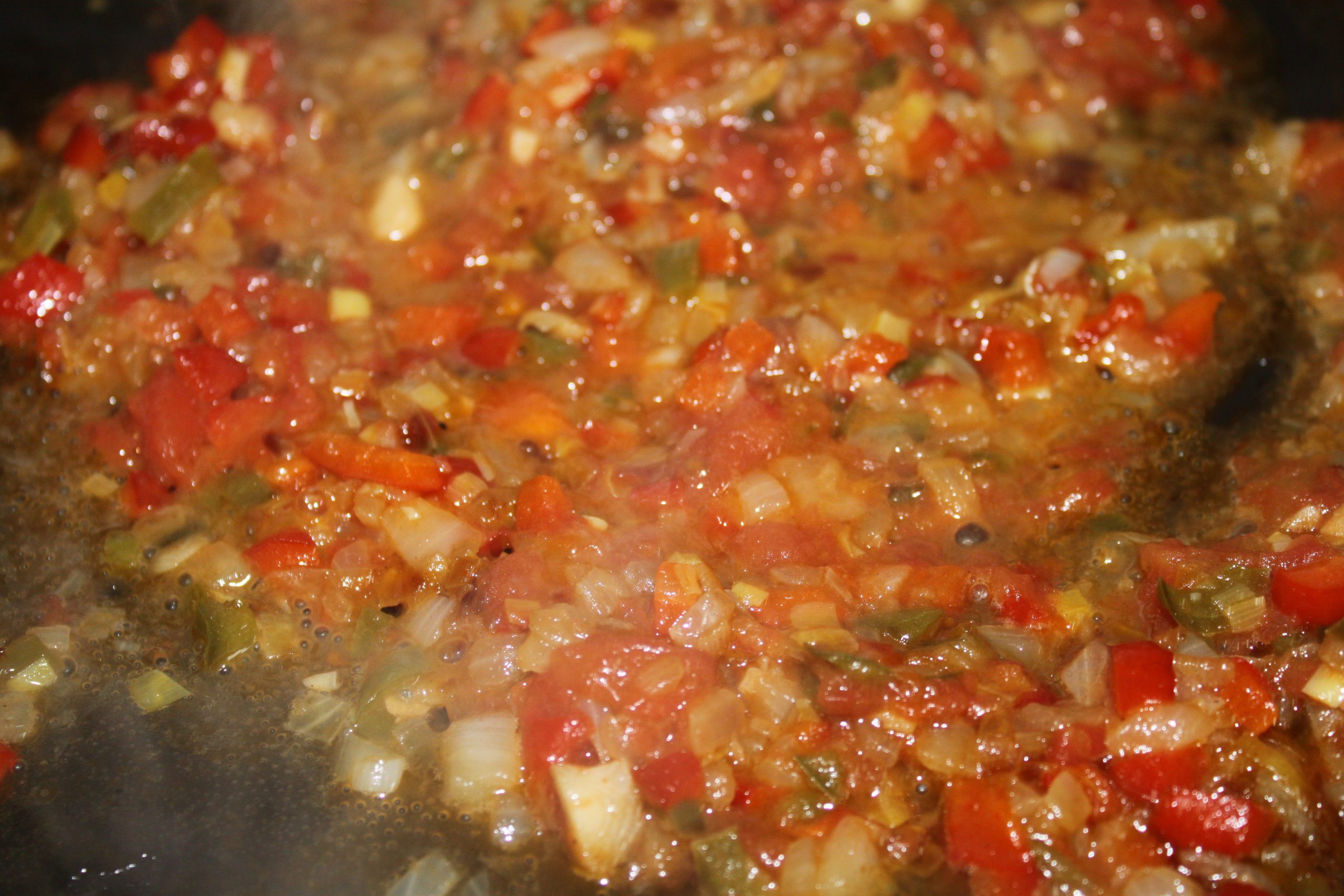 Tomate rallado y pimentón integrándose en el sofrito base de la zarzuela de pescado.