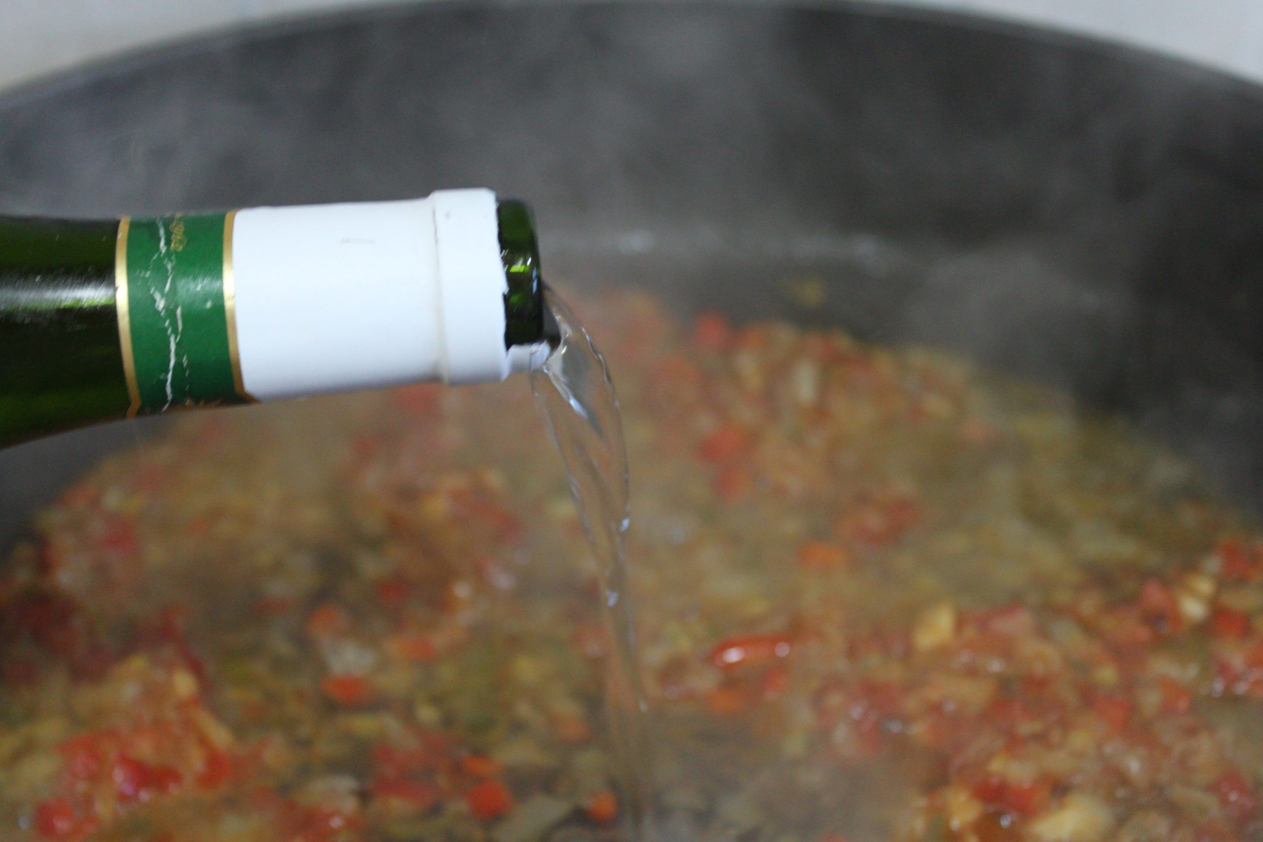 Vino blanco reduciéndose junto al sofrito de verduras en la cazuela.