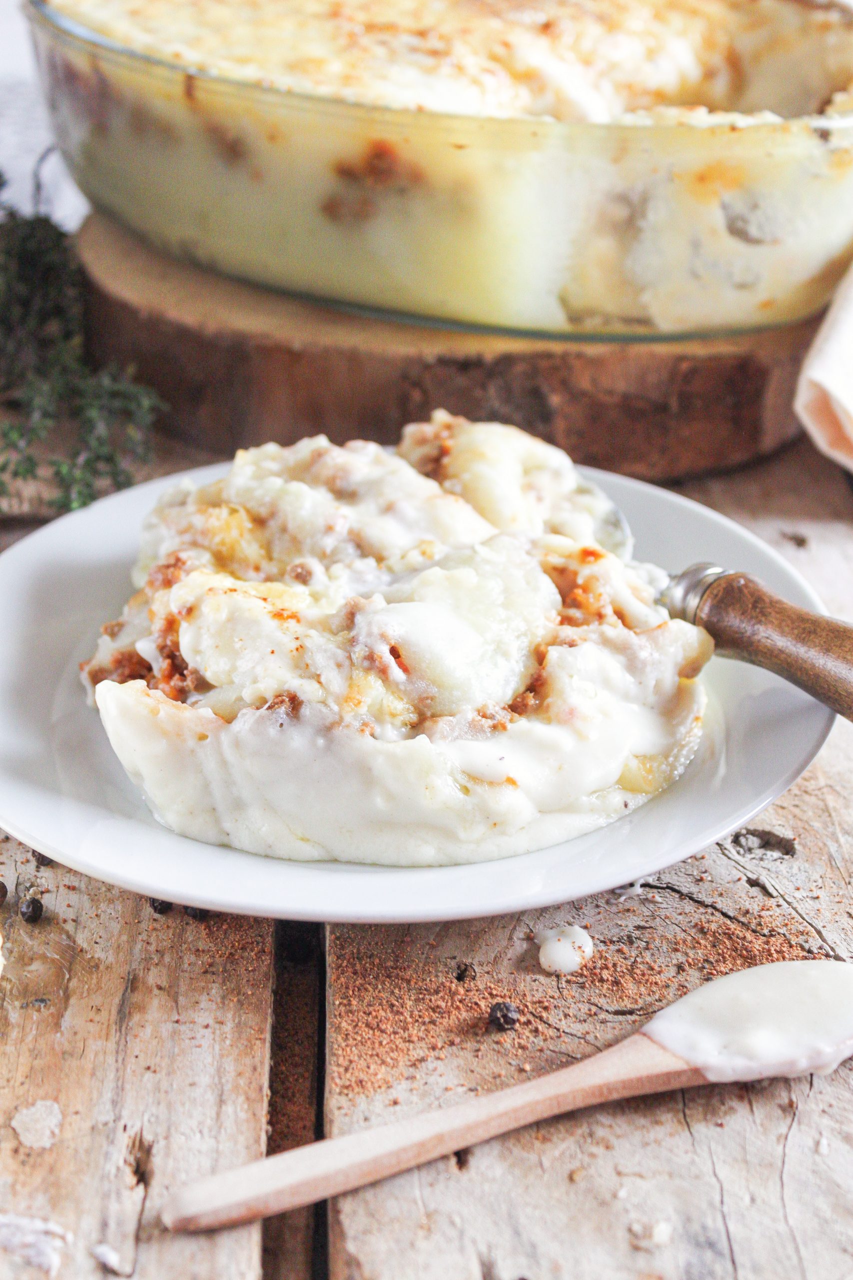 Ración de pastel de patata y carne gratinado servido en plato rústico de cocina con alma