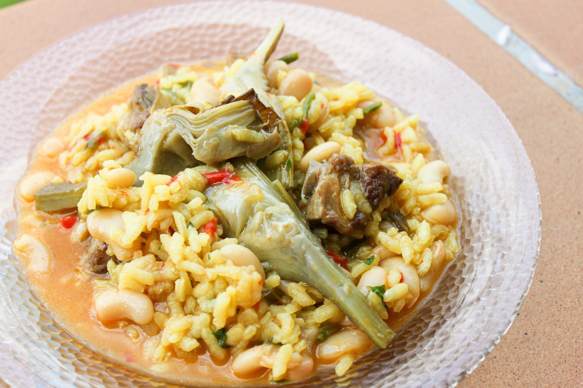 Arroz meloso en paella con costilla ibérica, espárragos verdes y alcachofas