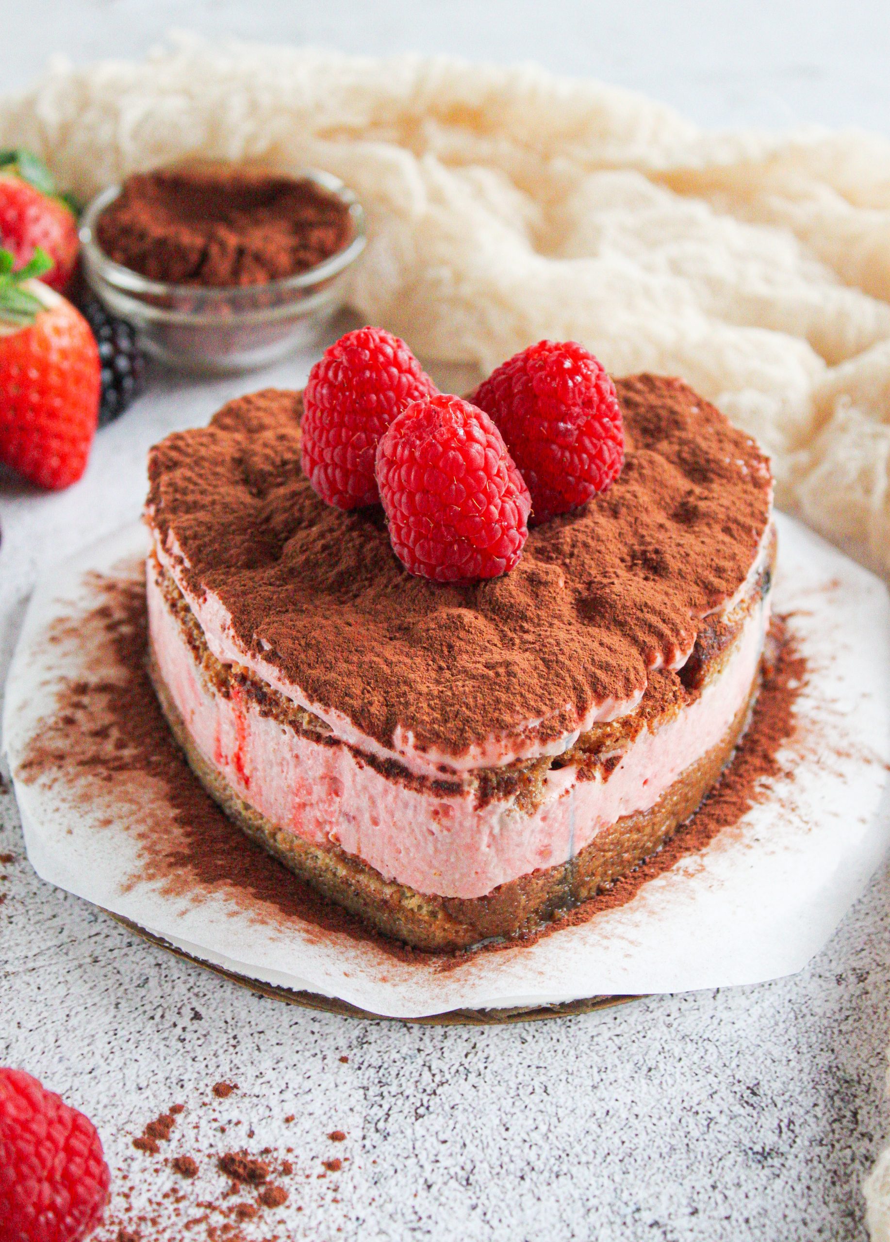 Tiramisú en forma de corazón decorado con frambuesas y cacao en polvo