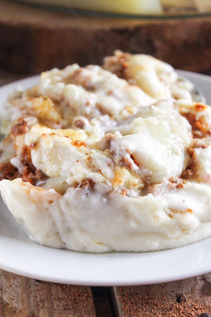 Ración de pastel de patata y carne gratinado servido en plato rústico de cocina con alma