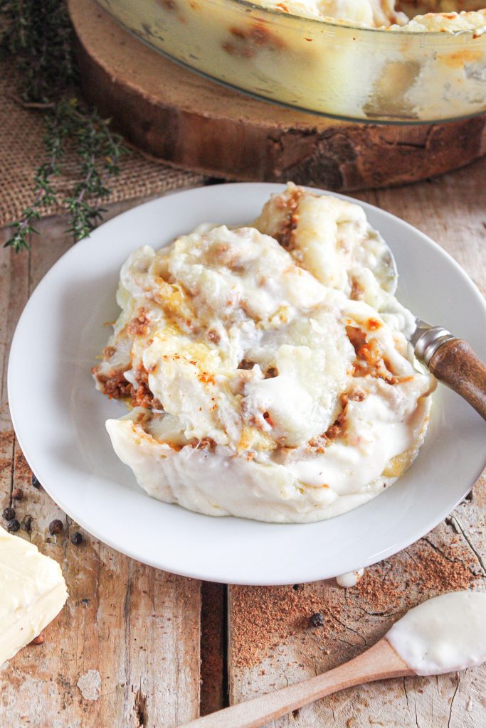 Raci&oacute;n de pastel de patata y carne gratinado servido en plato r&uacute;stico de cocina con alma