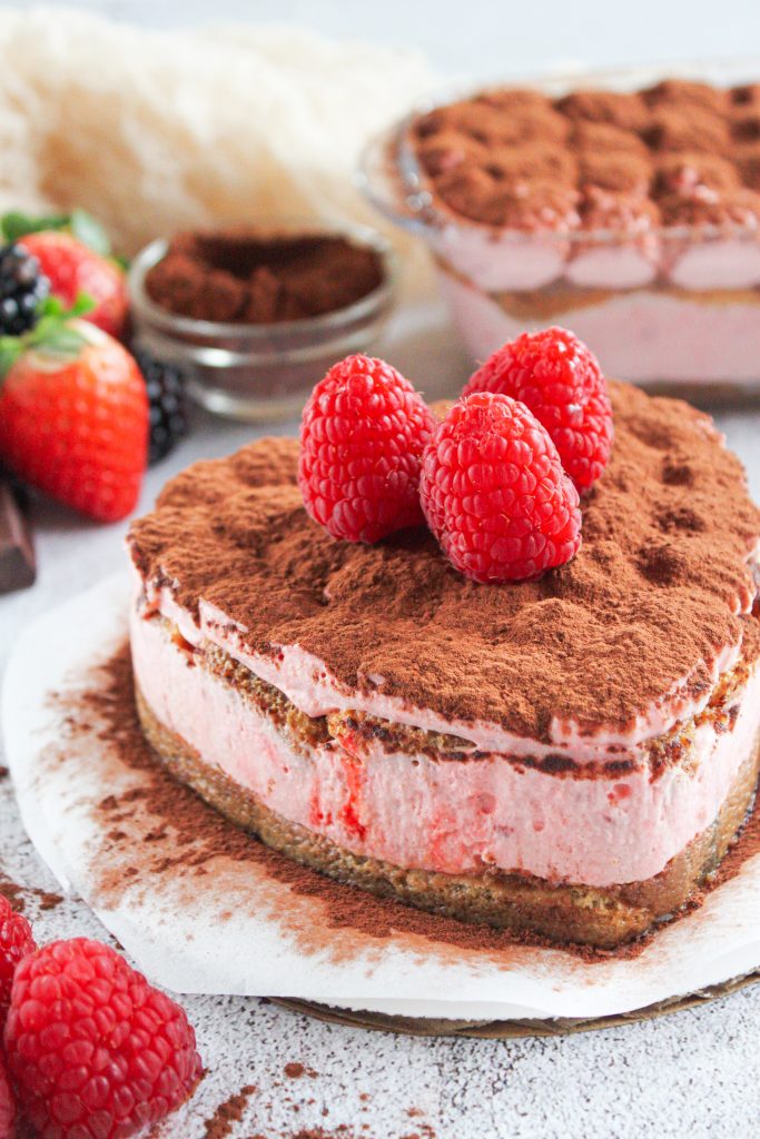 Tiramis&uacute; en forma de coraz&oacute;n decorado con frambuesas y cacao en polvo