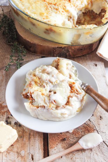 Ración de pastel de patata y carne gratinado servido en plato rústico de cocina con alma
