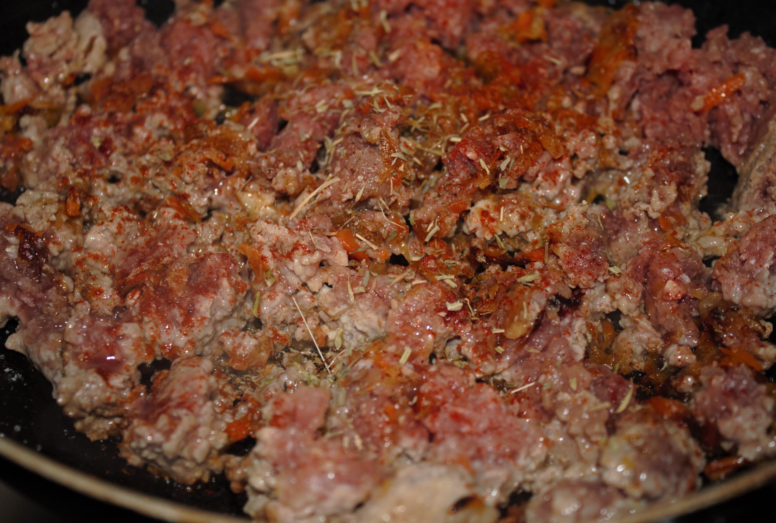 Cocinando carne picada con especias y hierbas provenzales en la sartén