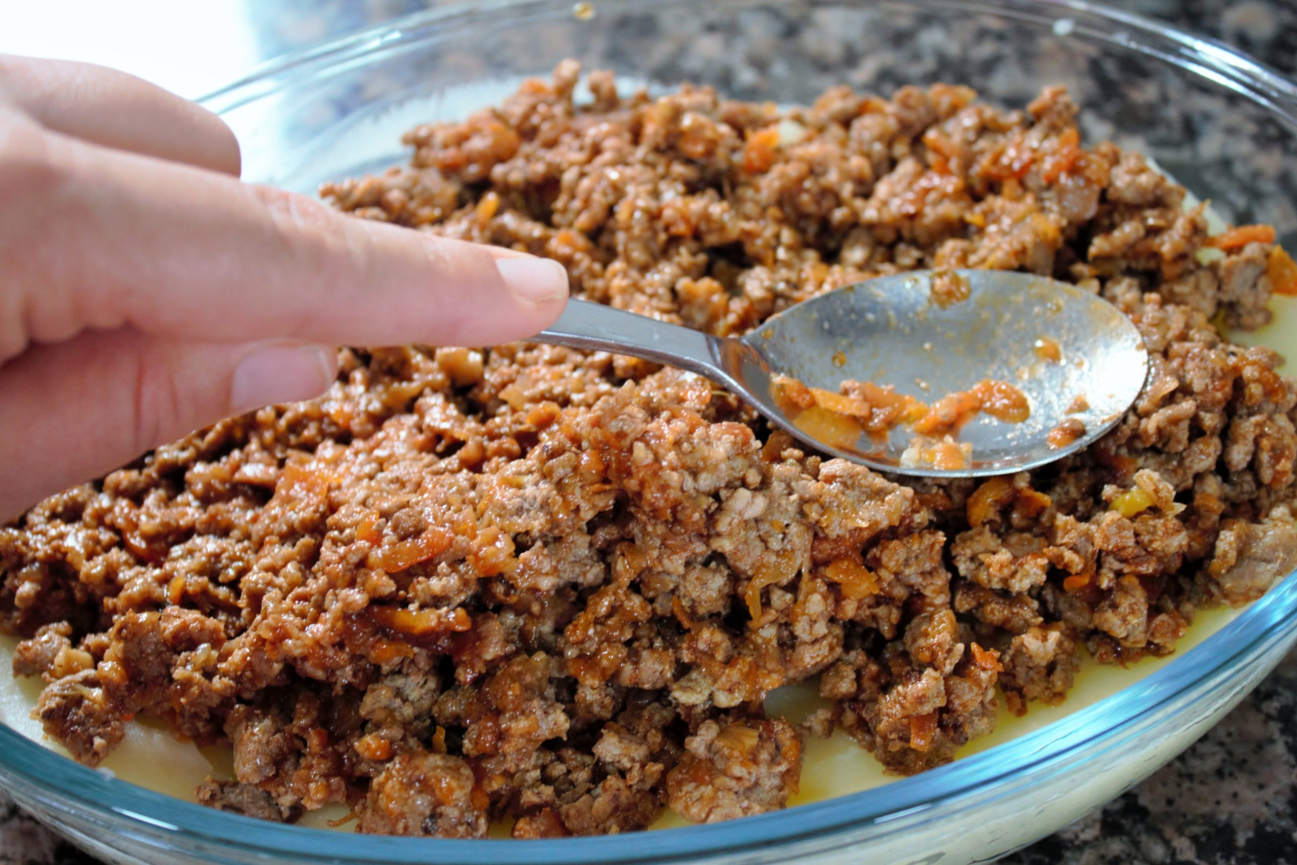 Montaje de capas de puré de patata y carne en fuente para horno
