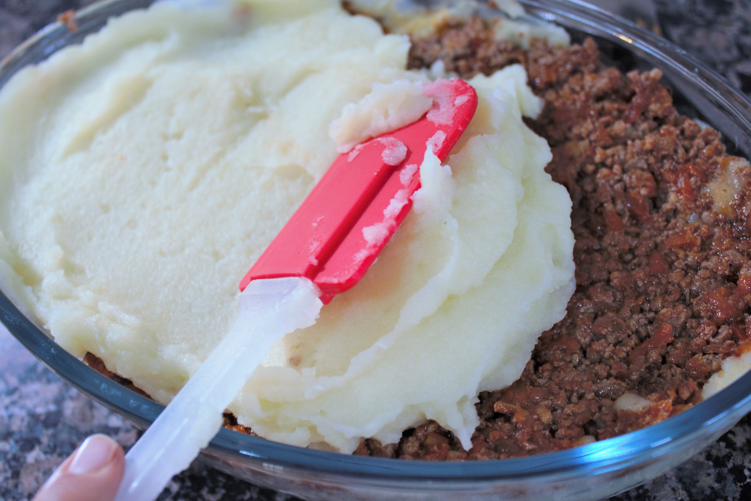 Montaje de capas de puré de patata y carne en fuente para horno