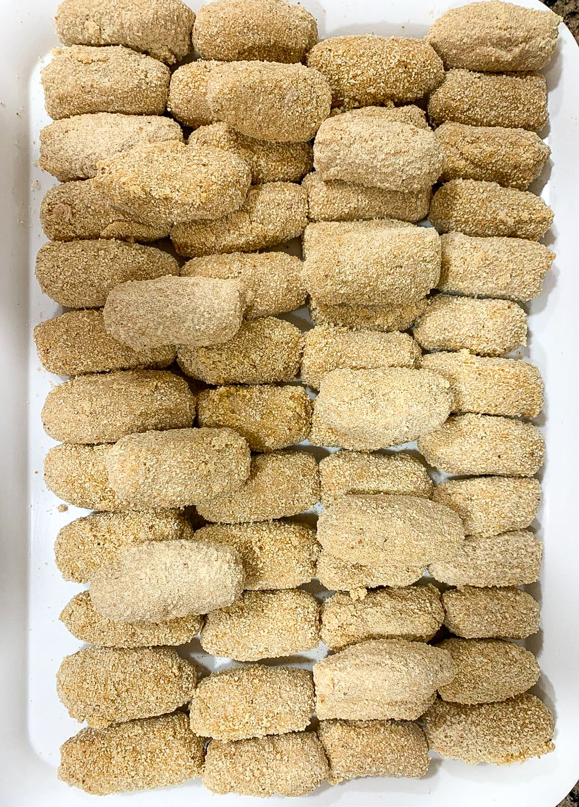 Croquetas antes de congelar colocadas sobre una bandeja listas para entrar en el congelador.