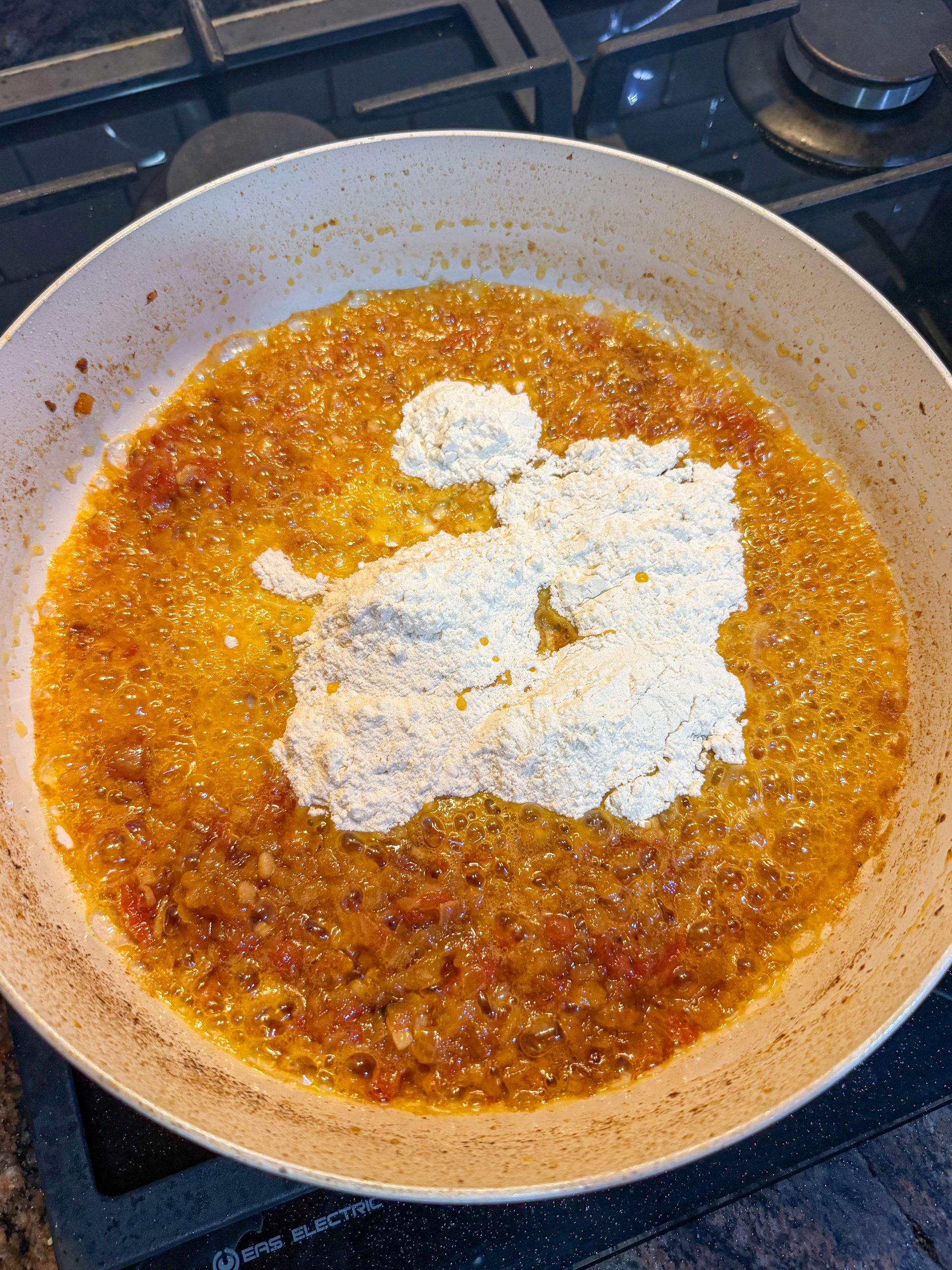 Harina añadida al sofrito y la mantequilla para elaborar el roux base de unas croquetas caseras tradicionales.