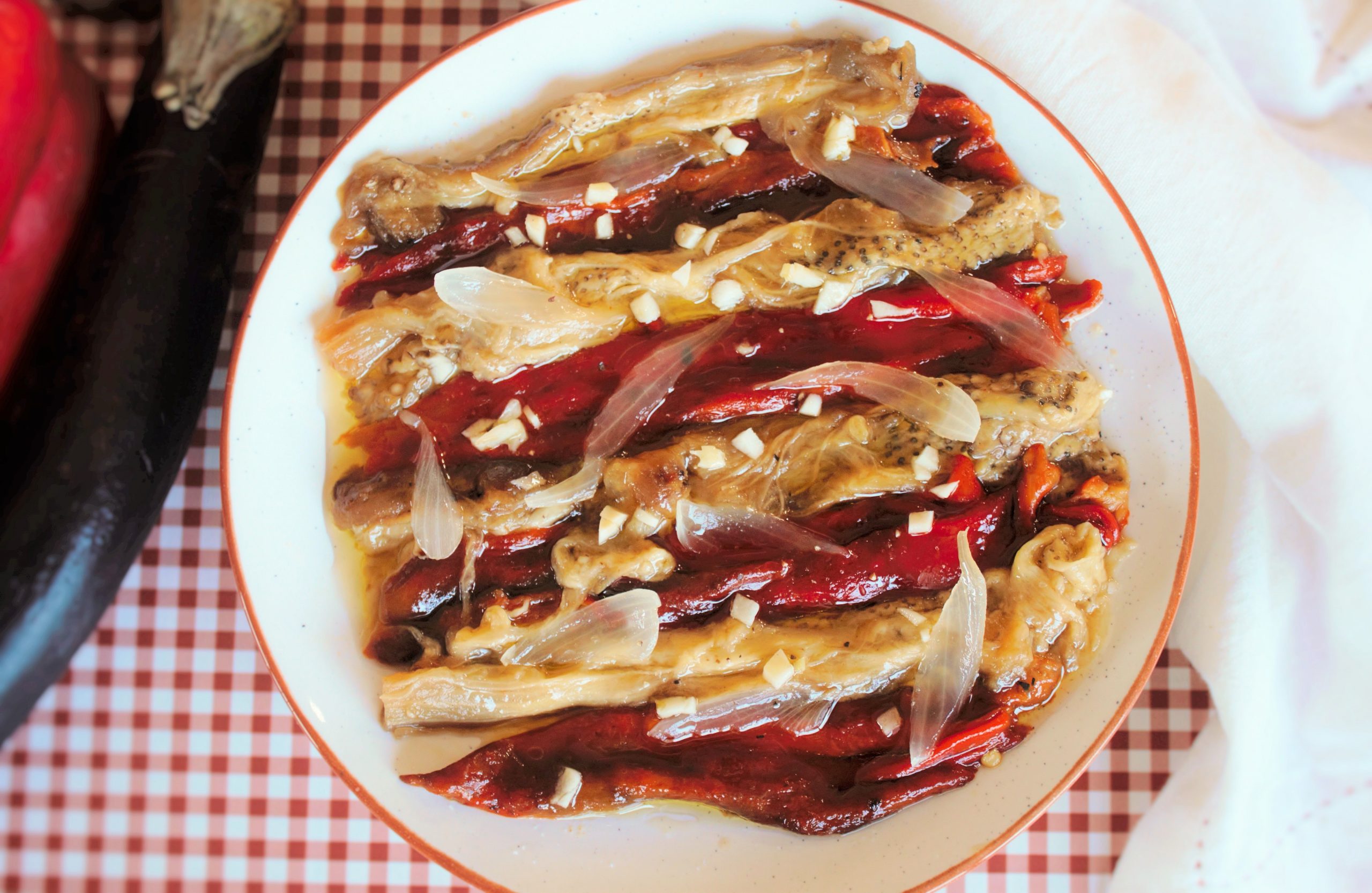 Escalivada a la brasa sobre plato rustico decorada con ajo picado y aceite de Oliva virgen extra.