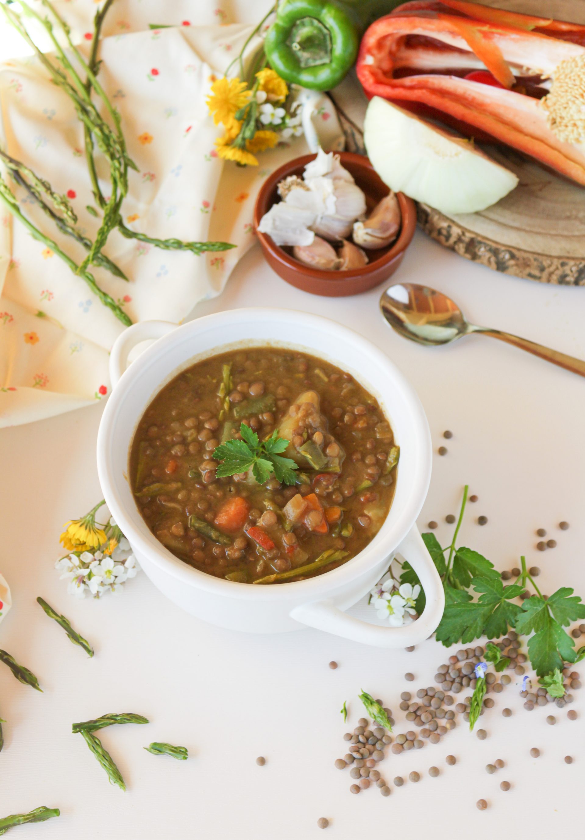 Cazuela de lentejas caseras de la abuela con espárragos trigueros silvestres, servidas en un cuenco de cerámica rústica con una ramita de tomillo fresco.