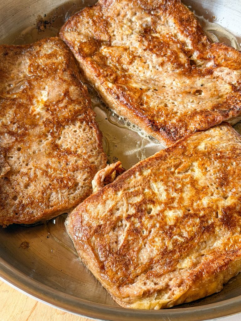 Torrijas de pan de brioche y cacao haciéndose a la plancha con mantequilla en una sartén antiadherente.