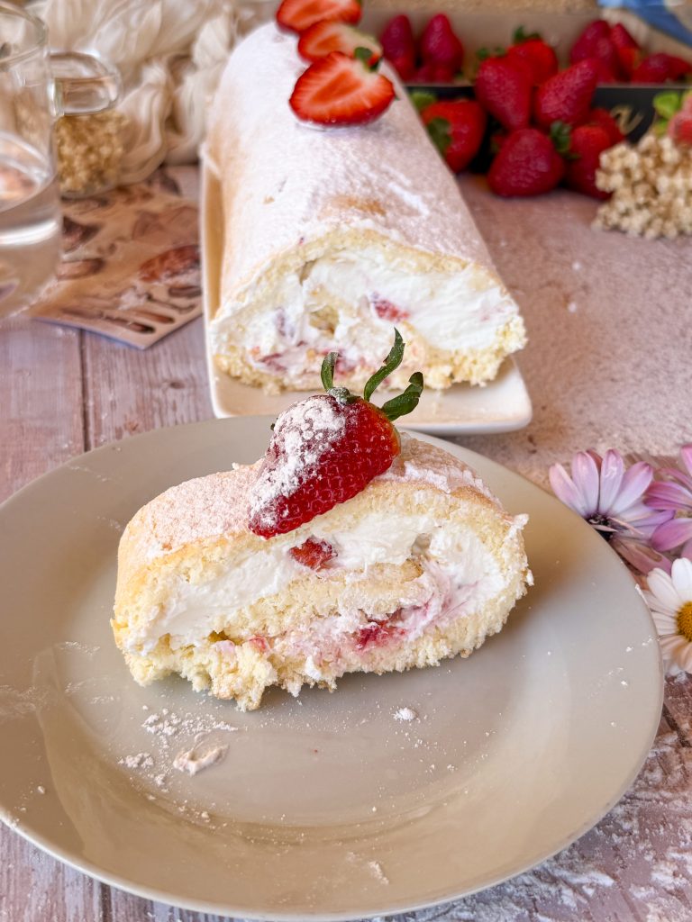Primer plano de un bizcocho enrollado relleno de nata firme y trozos de fresas frescas naturales.