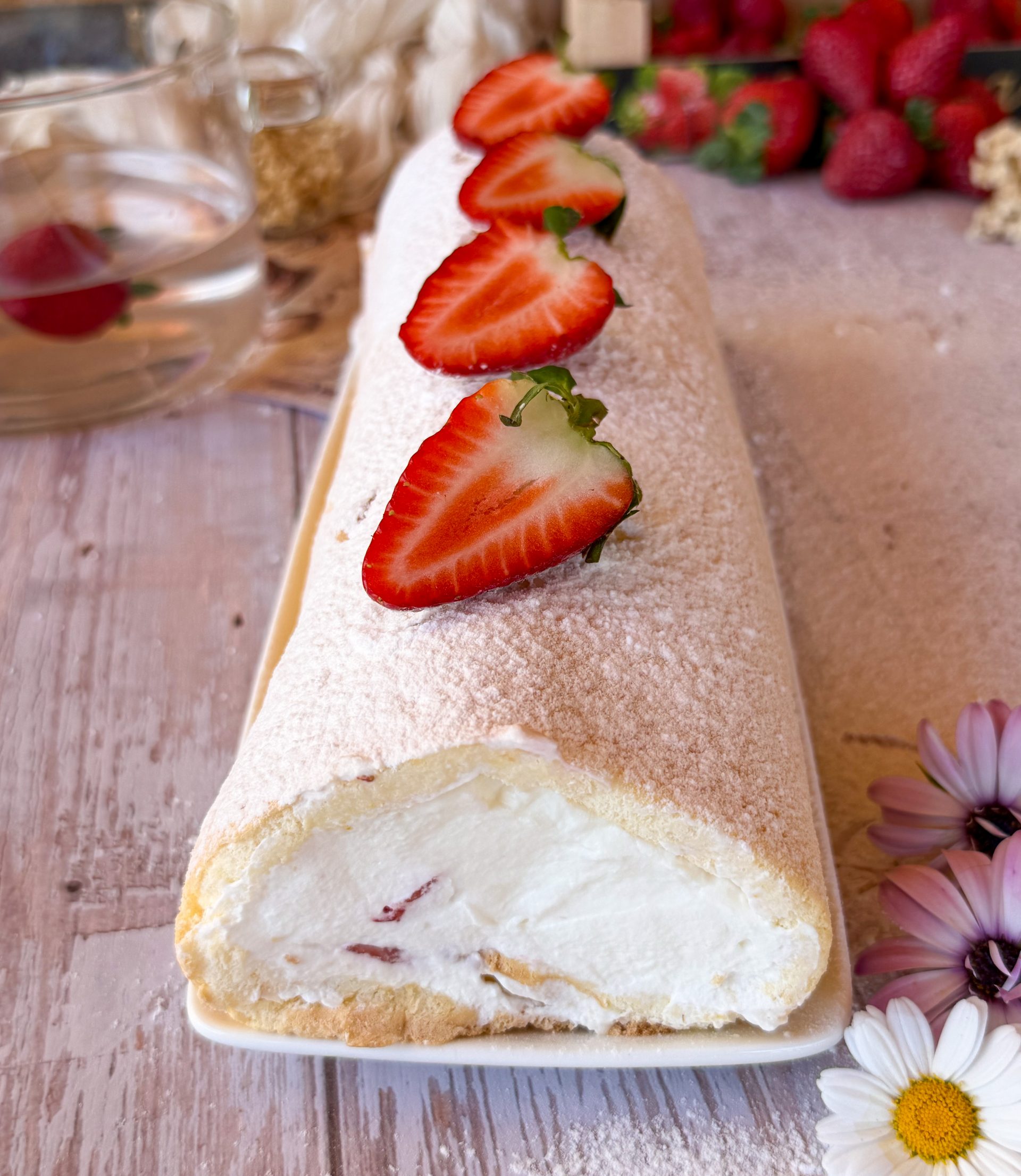 Primer plano de un bizcocho enrollado relleno de nata firme y trozos de fresas frescas naturales.