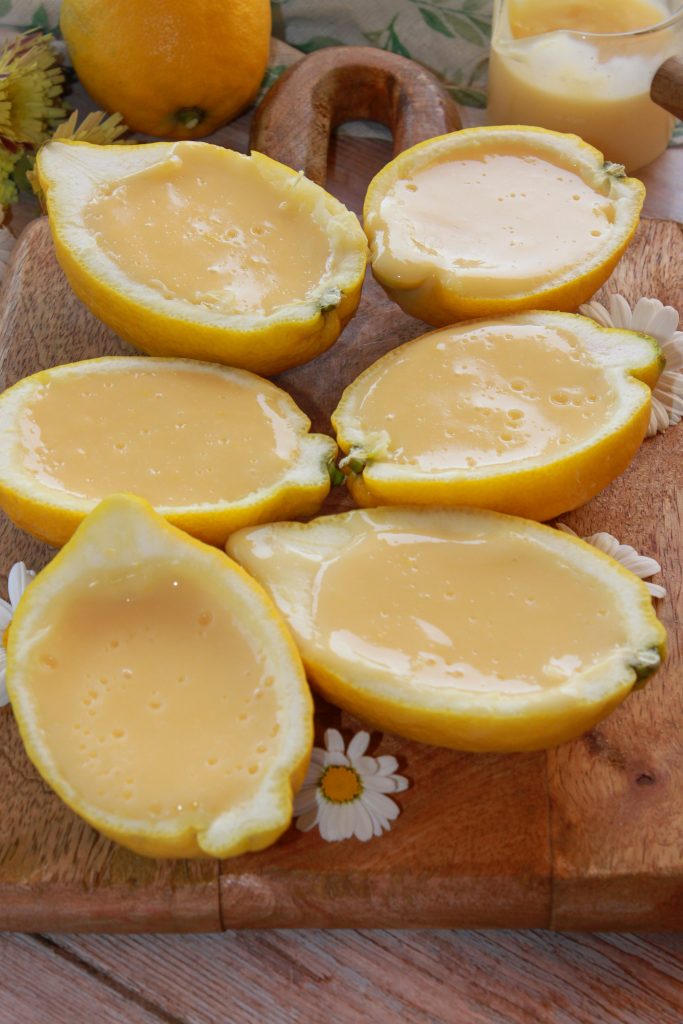 Postre de limones naturales rellenos de crema de limón suave y esponjosa sobre una mesa de madera rústica estilo soulfood