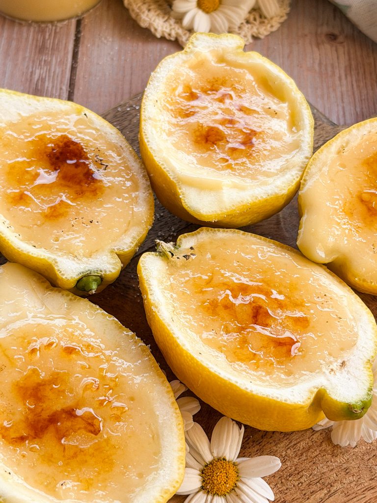 Postre de limones naturales rellenos de crema de limón suave y esponjosa sobre una mesa de madera rústica estilo soulfood