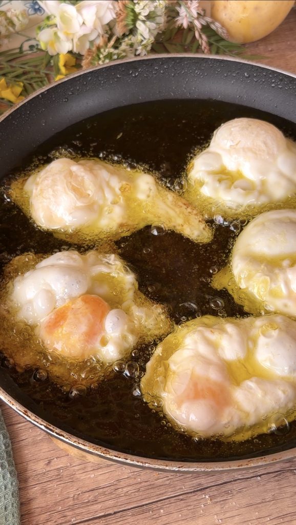 Huevos fritos fri&eacute;ndose en abundante aceite caliente burbujeando.