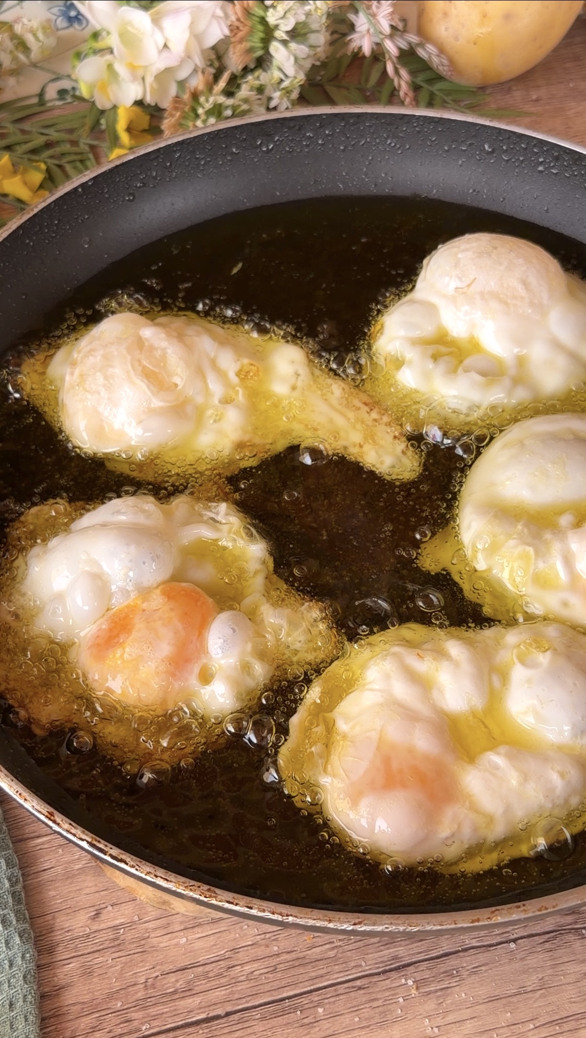 Huevos fritos friéndose en abundante aceite caliente burbujeando.