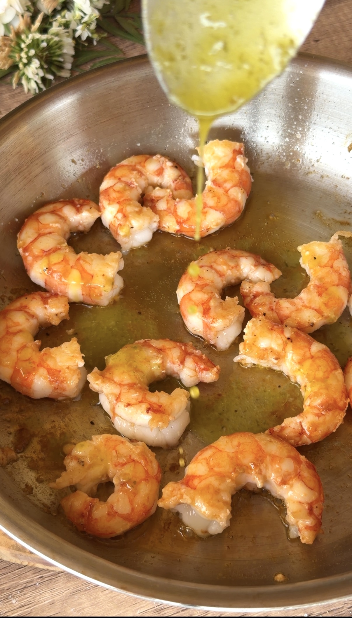 Gambones pelados salteándose en una sartén con aceite de oliva virgen extra, mostrando el jugo anaranjado y el brillo del marisco recién cocinado.