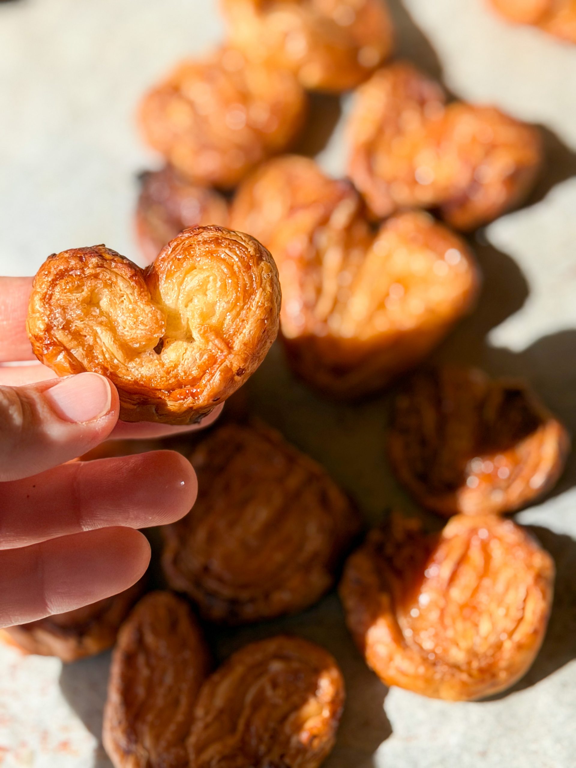 Palmeritas de hojaldre caseras muy doradas y caramelizadas con azúcar, dispuestas de forma estética sobre una superficie de madera rústica.