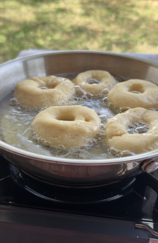 Donuts caseros dorándose en aceite en una sartén