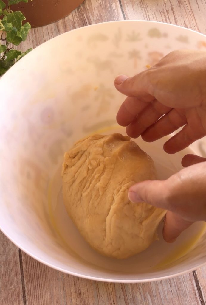 Bola de masa de donuts caseros reposando en un bol aceitado antes de fermentar