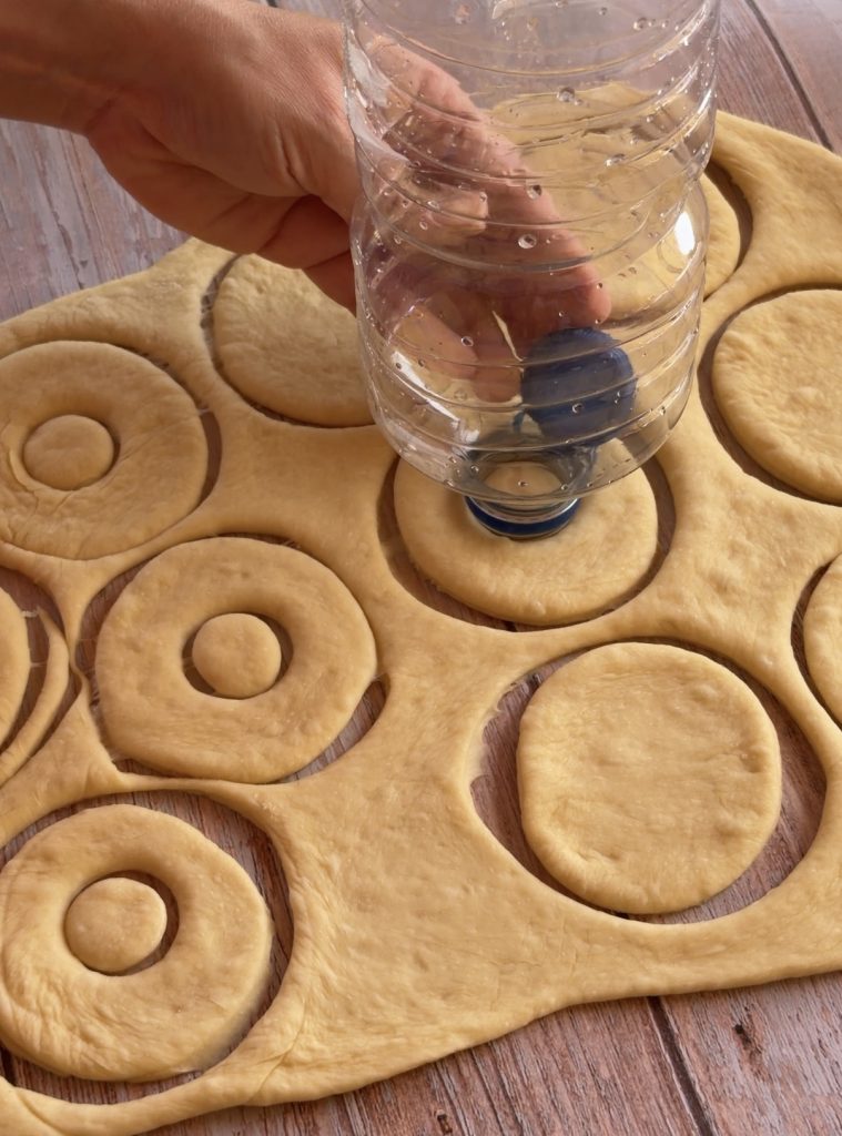 Donuts crudos cortados sobre papel de horno antes de la segunda fermentación
