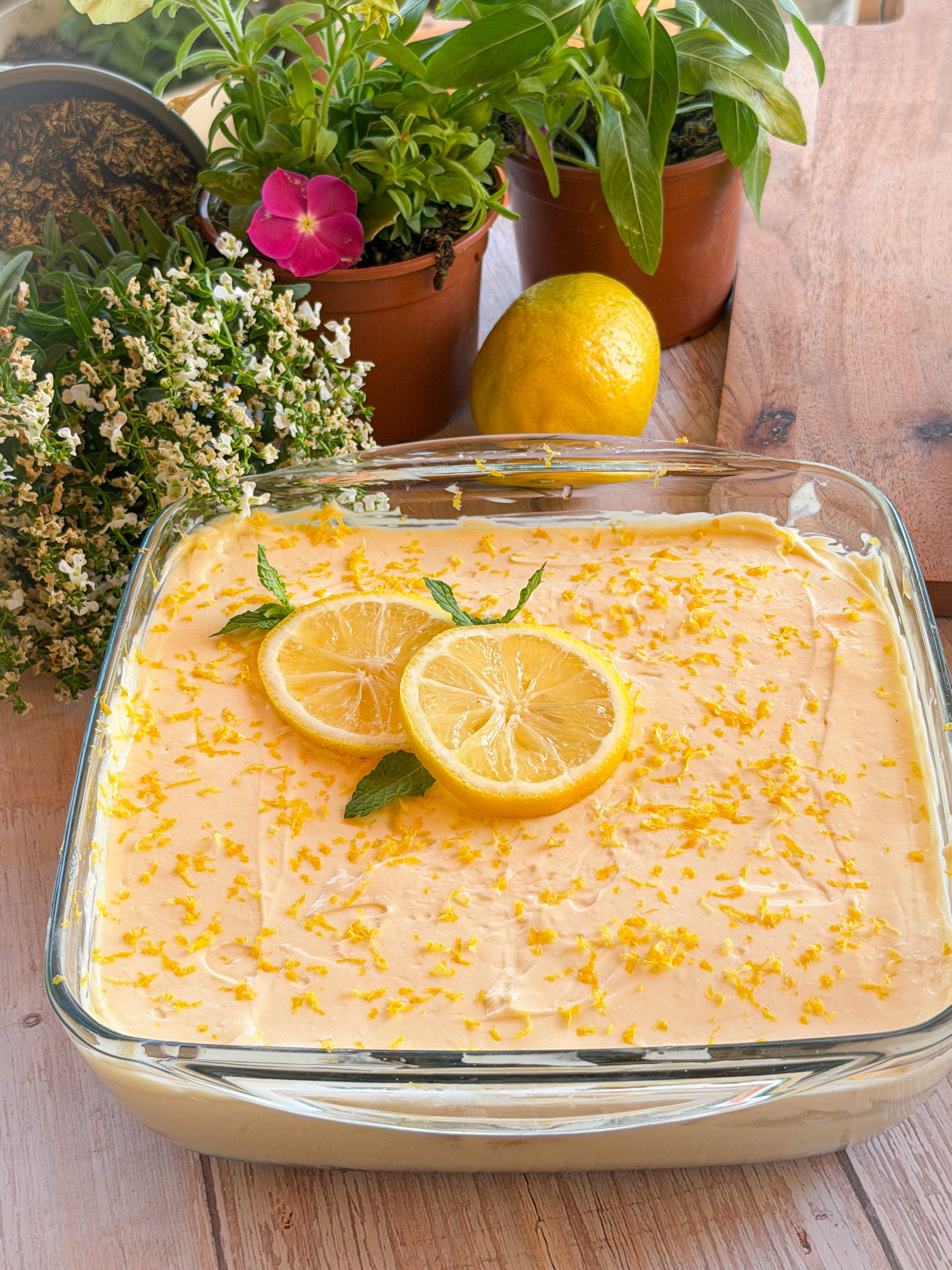 Tiramisú de limón casero en bandeja de cristal decorado con rodajas de limón, ralladura y hojitas de menta