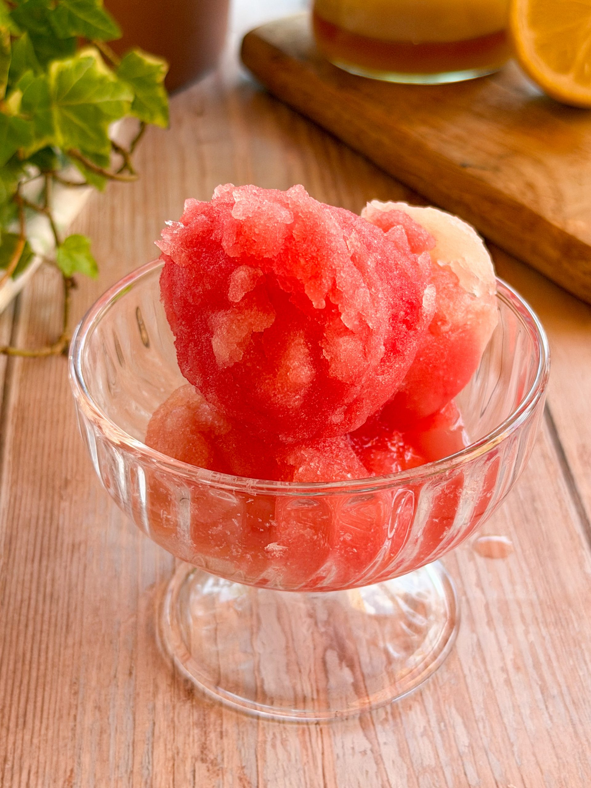Bola de sorbete bicolor (sandía y melón) servida en un cuenco de cristal frío, lista para degustar.