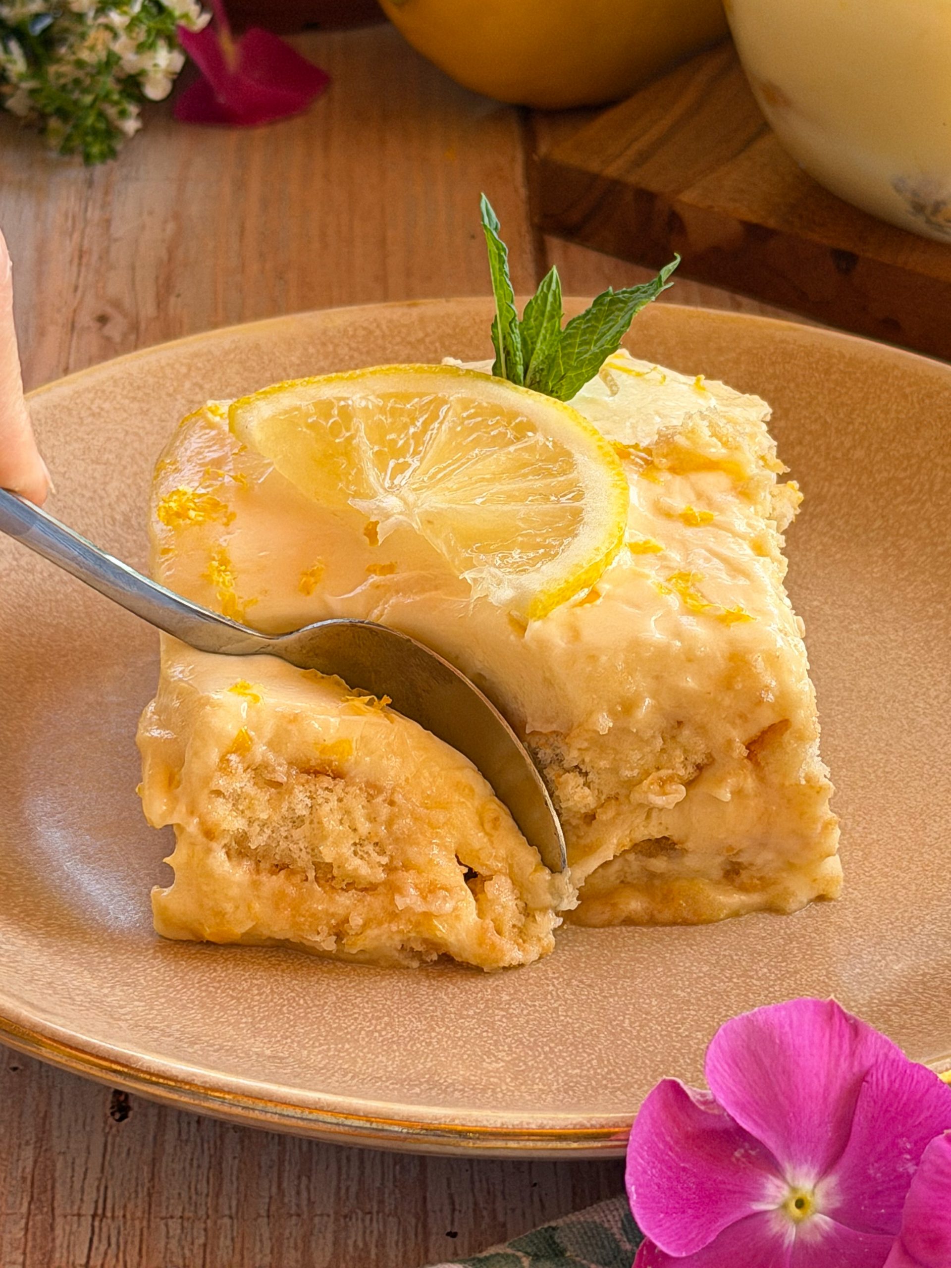 Porción de tiramisú de limón servida en plato, decorada con menta fresca