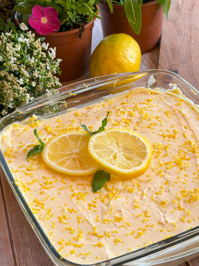 Tiramisú de limón casero en bandeja de cristal decorado con rodajas de limón, ralladura y hojitas de menta